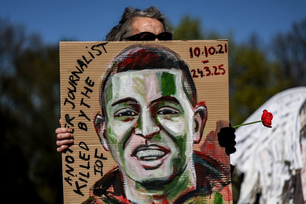 epa12014200 A protester holds a portrait depicting a dead journalist during a symbolic funeral procession in solidarity with the people killed in Gaza and the West Bank, in Berlin, Germany, 06 April 2025. EPA-EFE/FILIP SINGER