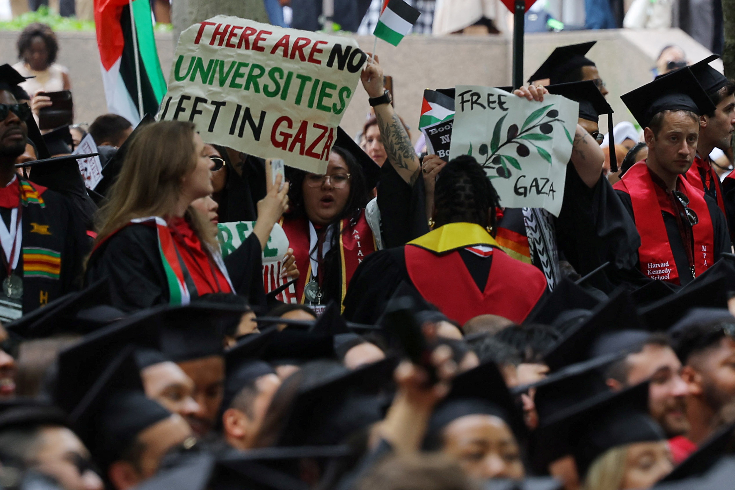 Graduating students hold a sign reading "There Are No Universities Left in Gaza".