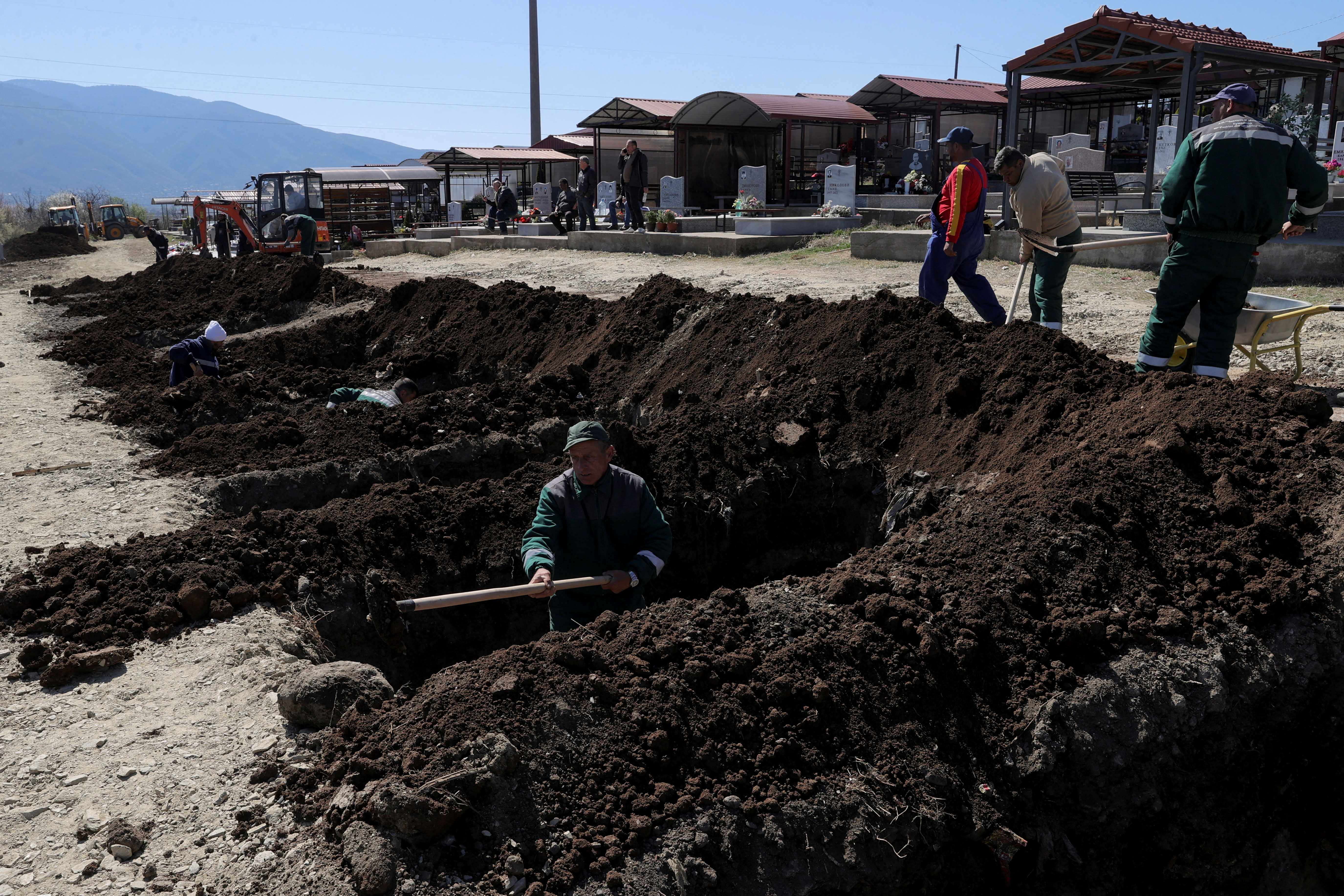 Workers prepare graves at a cemetery.