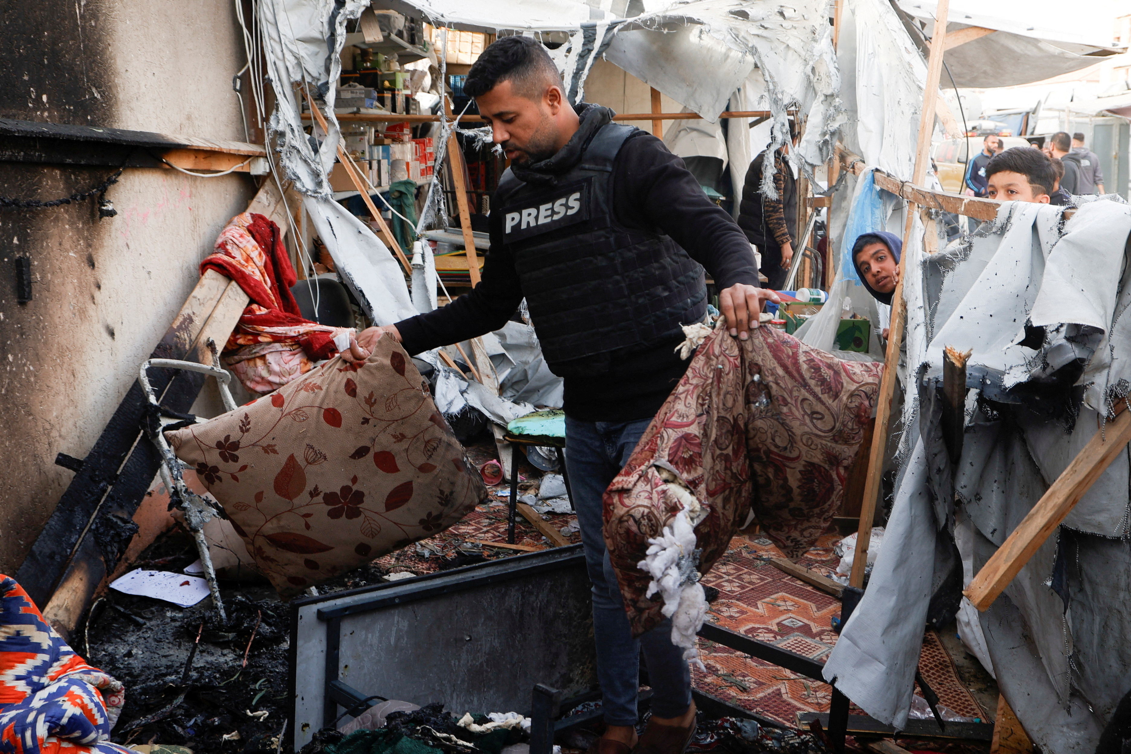 Palestinians inspect the damage to a tent housing journalists after it was hit by an Israeli strike