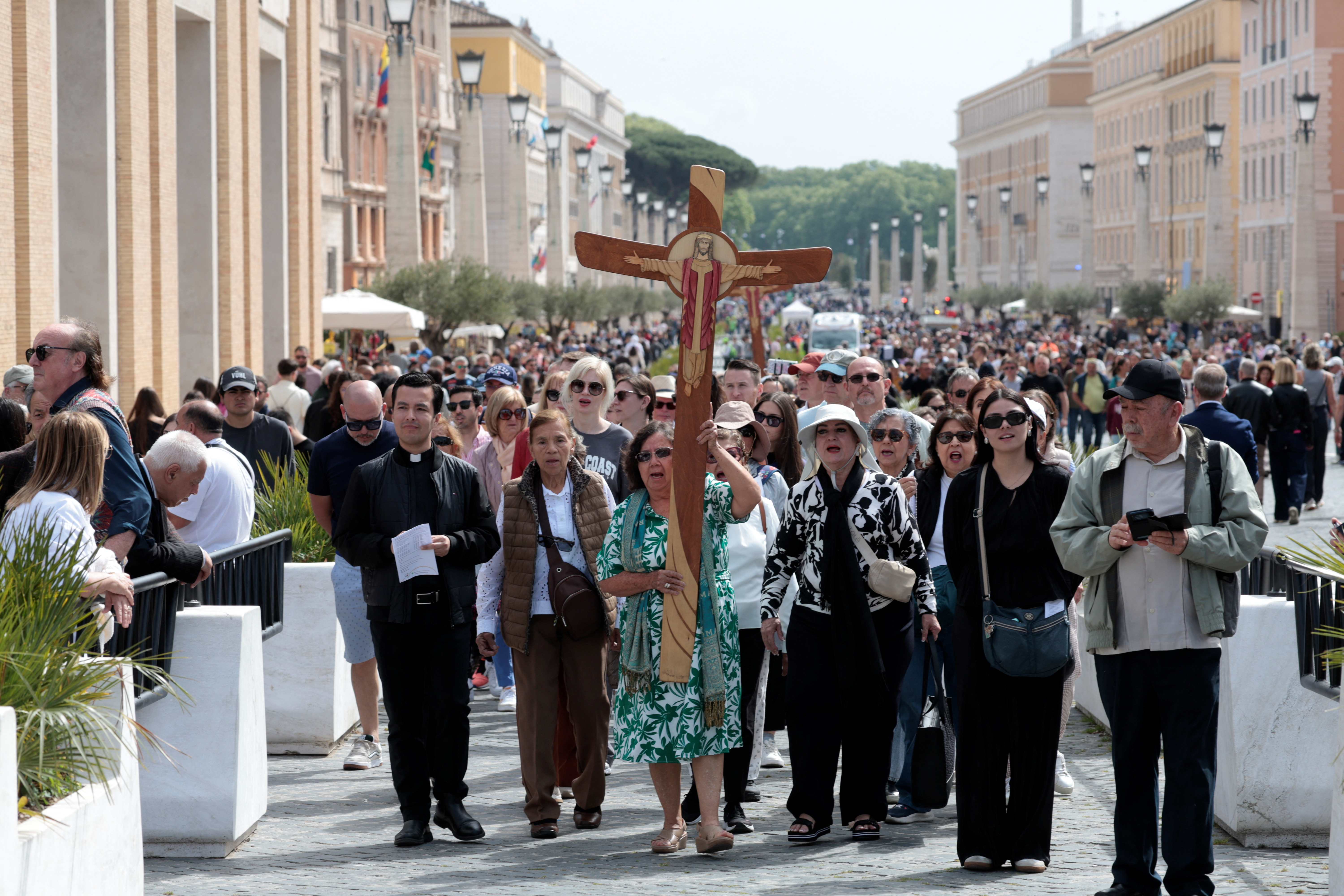 A woman carries a cross amid other people after the Vatican announced the death of Pope Francis in Rome