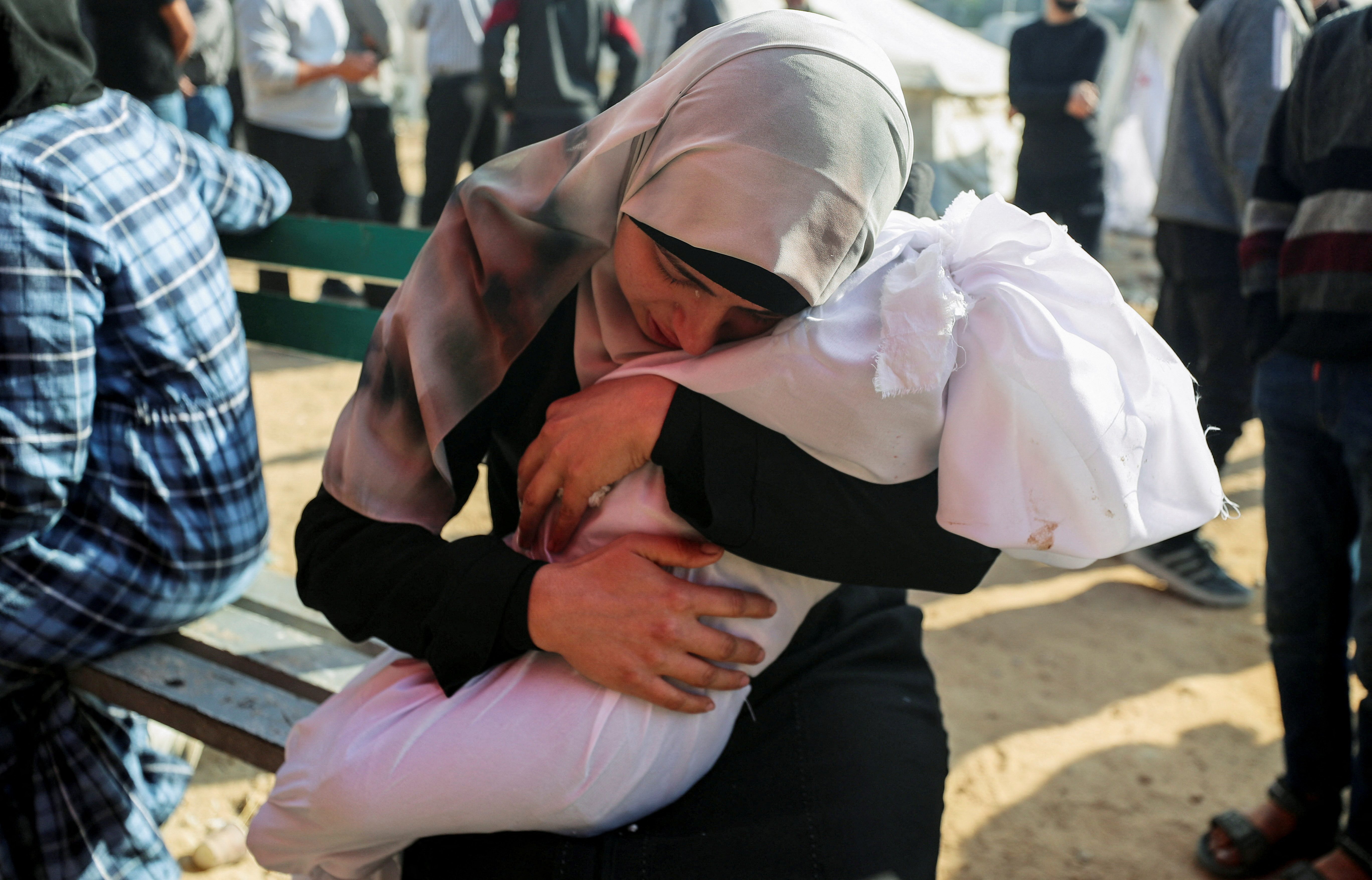 A woman reacts while holding the body of a Palestinian child killed in Israeli strikes