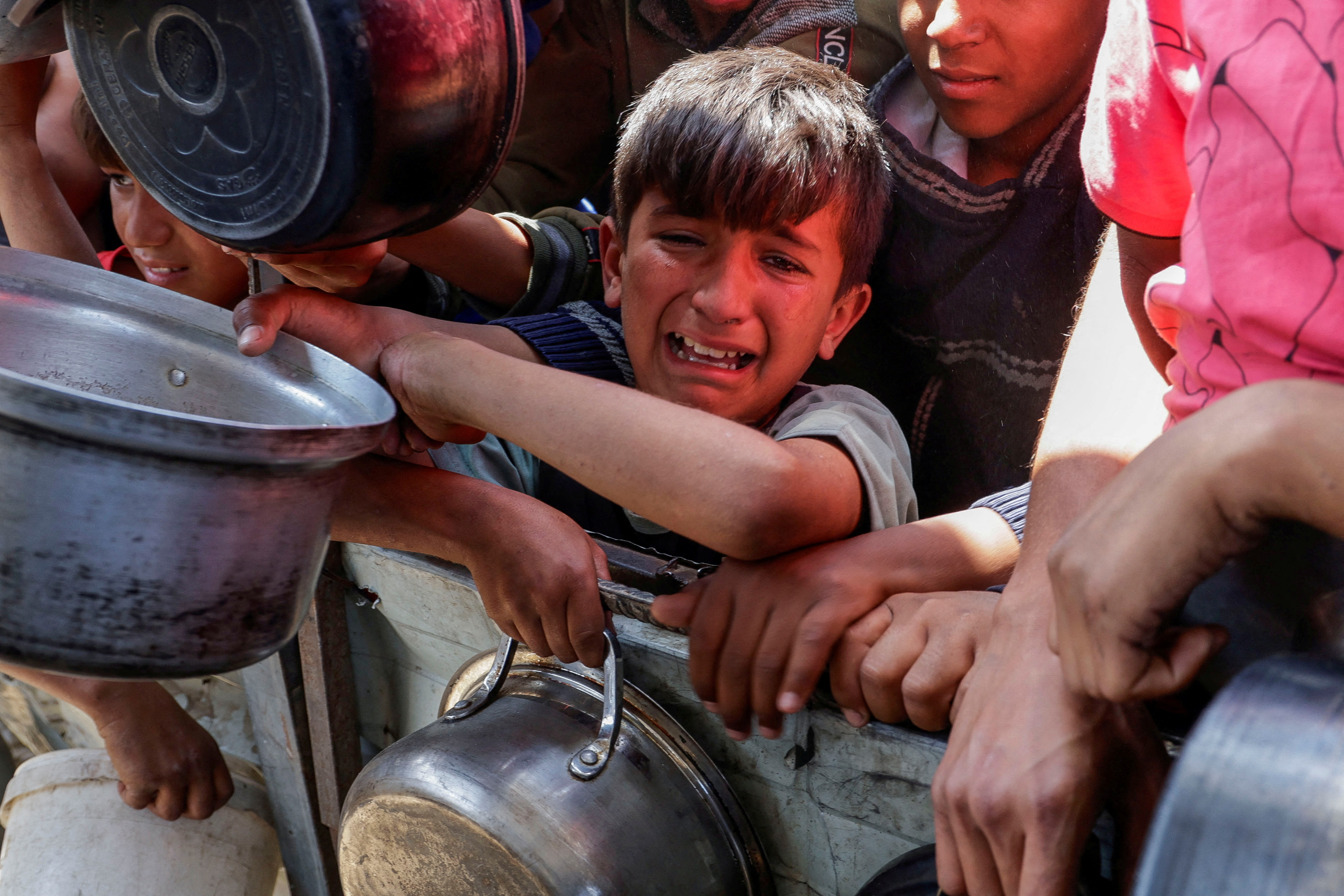 A Palestinian children cries as people gather to receive food in Gaza