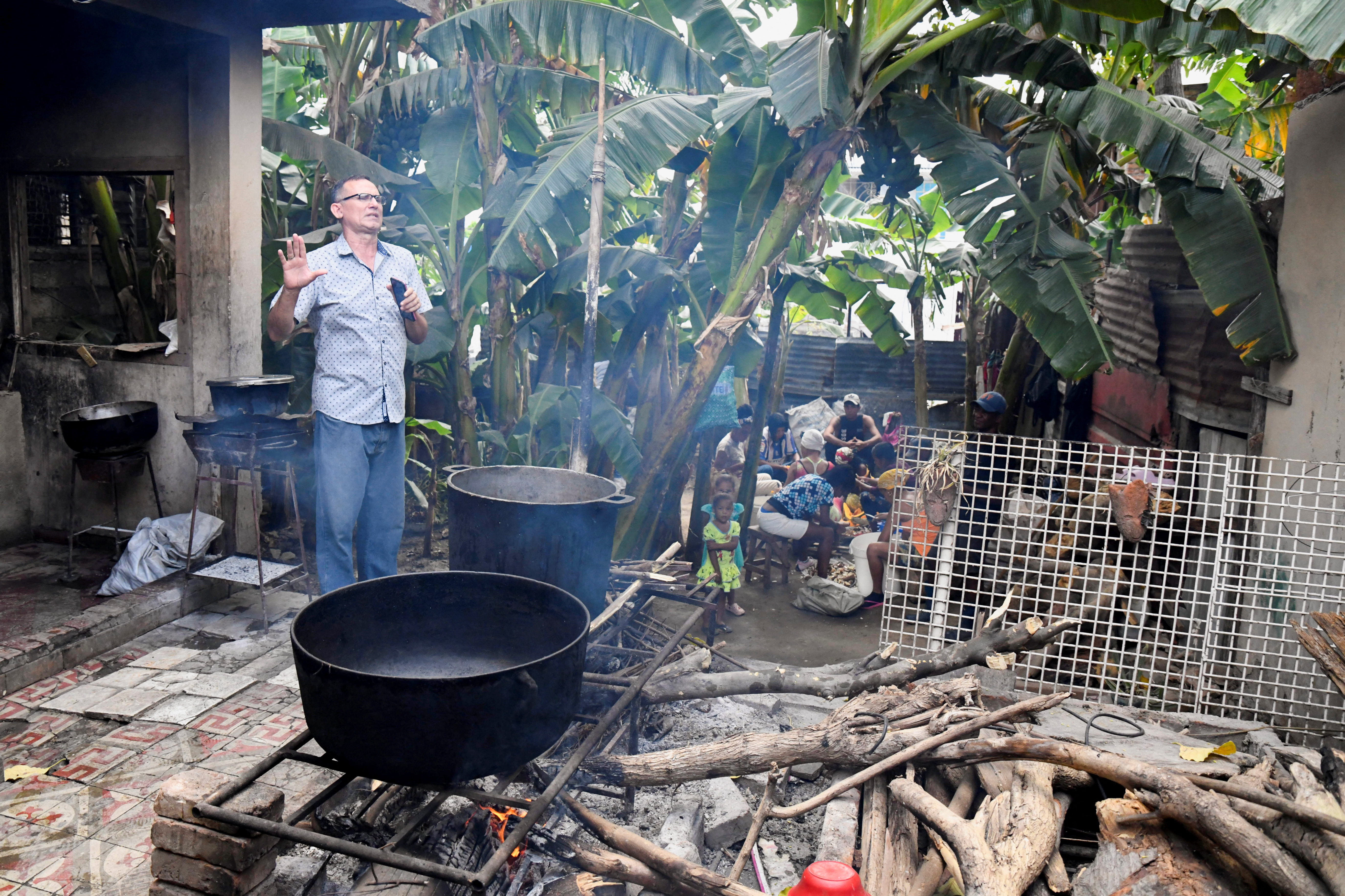 Jose Daniel Ferrer speaks next to a large castiron pot where food is cooking outdoors in Santiago de Cuba.