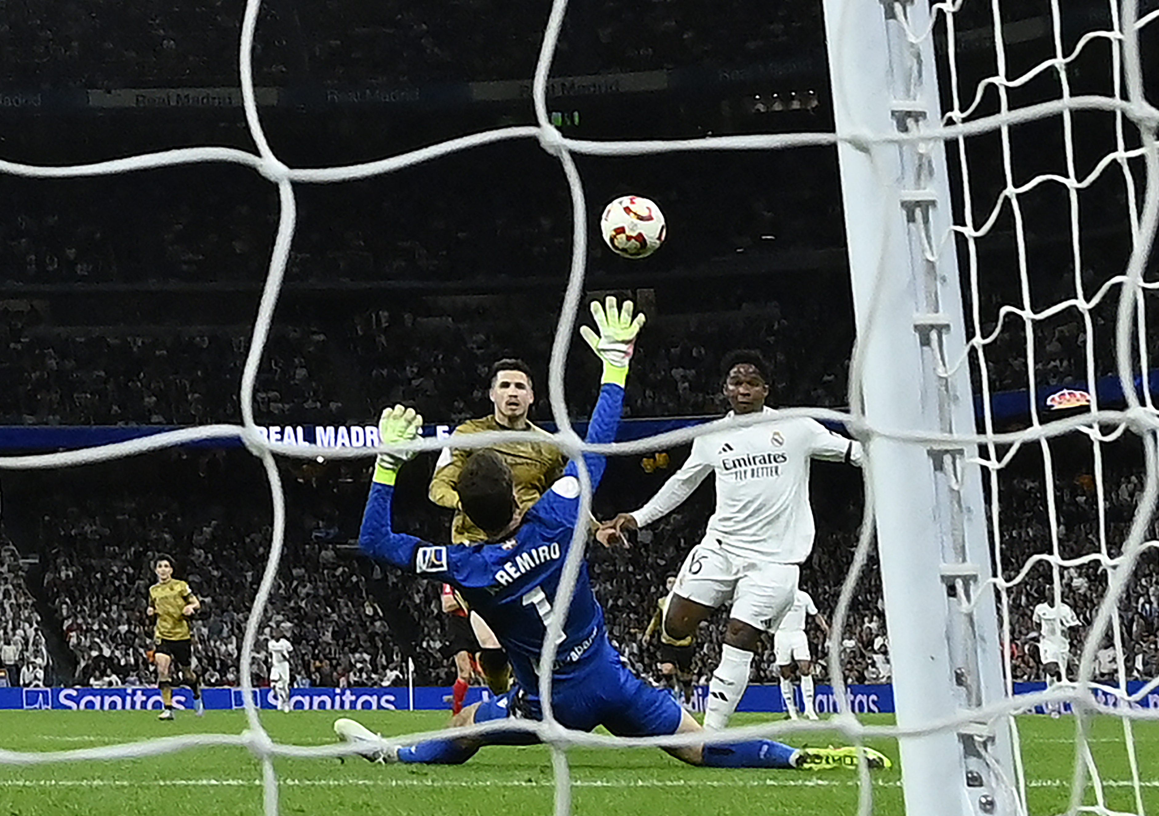 Real Madrid's Brazilian forward #16 Endrick (R) scores his team's first goal in spite of Real Sociedad's Spanish goalkeeper #01 Alex Remiro during the Spanish Copa del Rey (King's Cup) semi-final second leg football match between Real Madrid CF and Real Sociedad at the Santiago Bernabeu stadium in Madrid on April 1, 2025. (Photo by OSCAR DEL POZO / AFP)