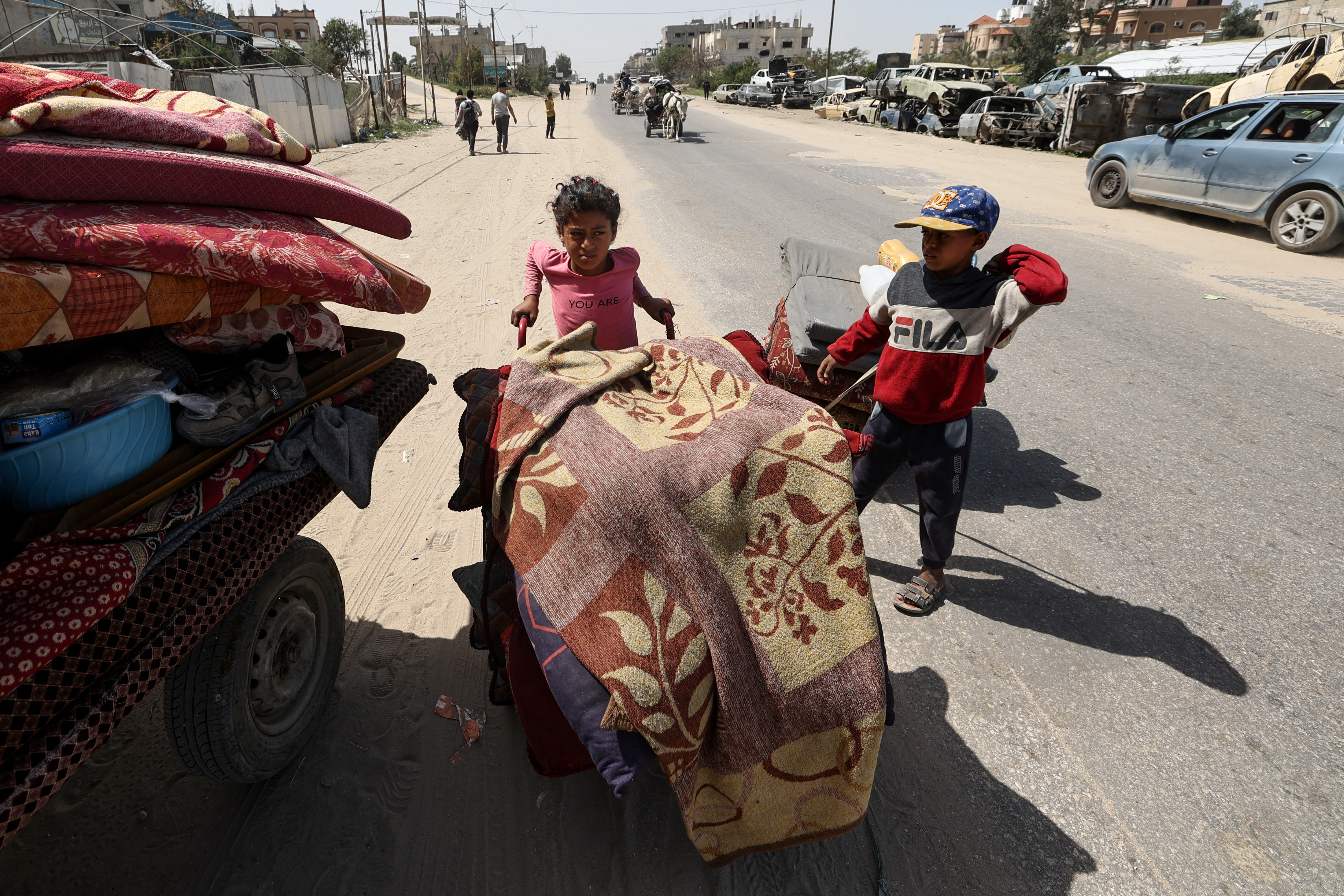 Children push carts loaded with belongings as Palestinians flee Rafah towards Khan Yunis in the southern Gaza Strip