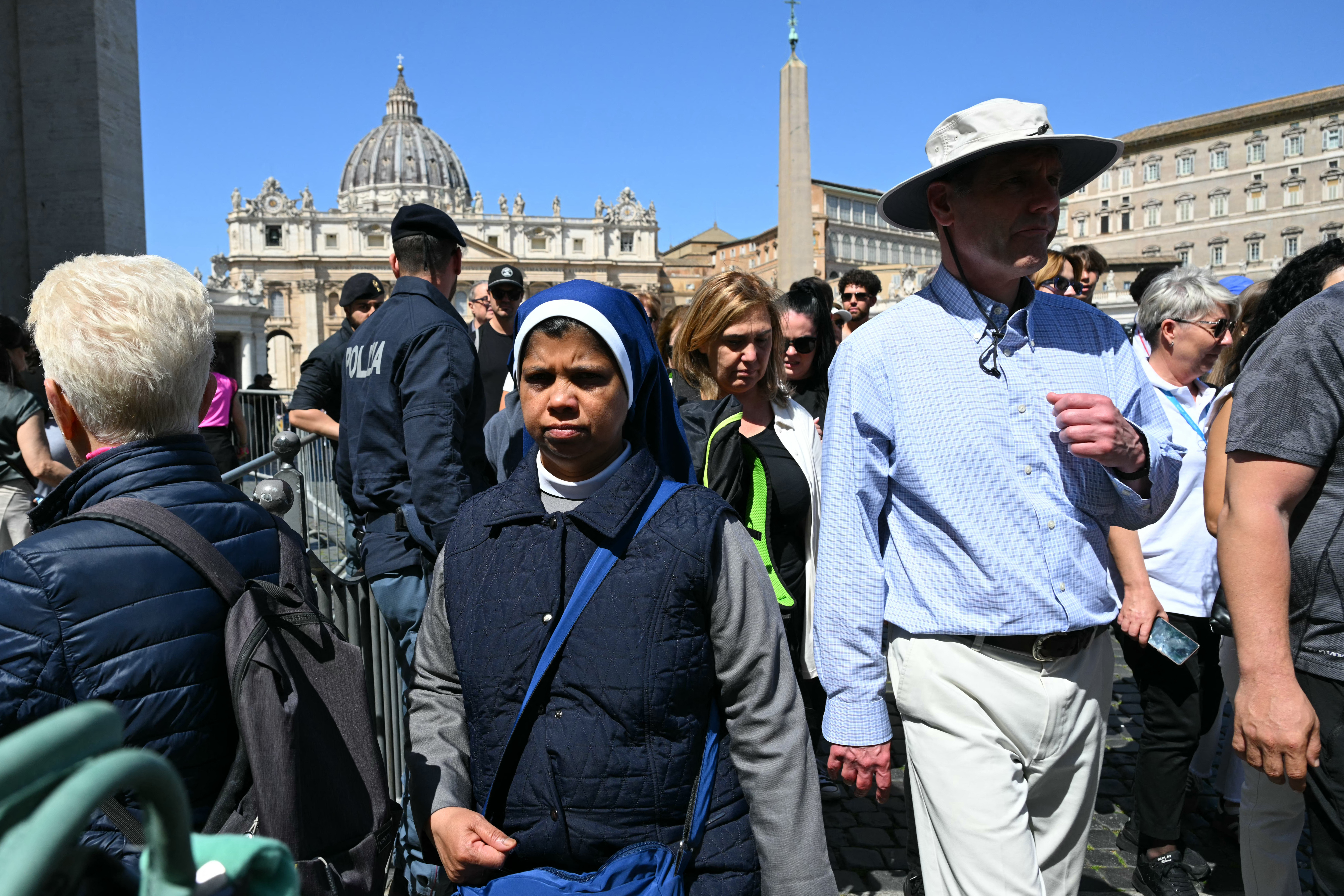 Visitors walk near St Peter's Square with St Peter's Basilica in the background.