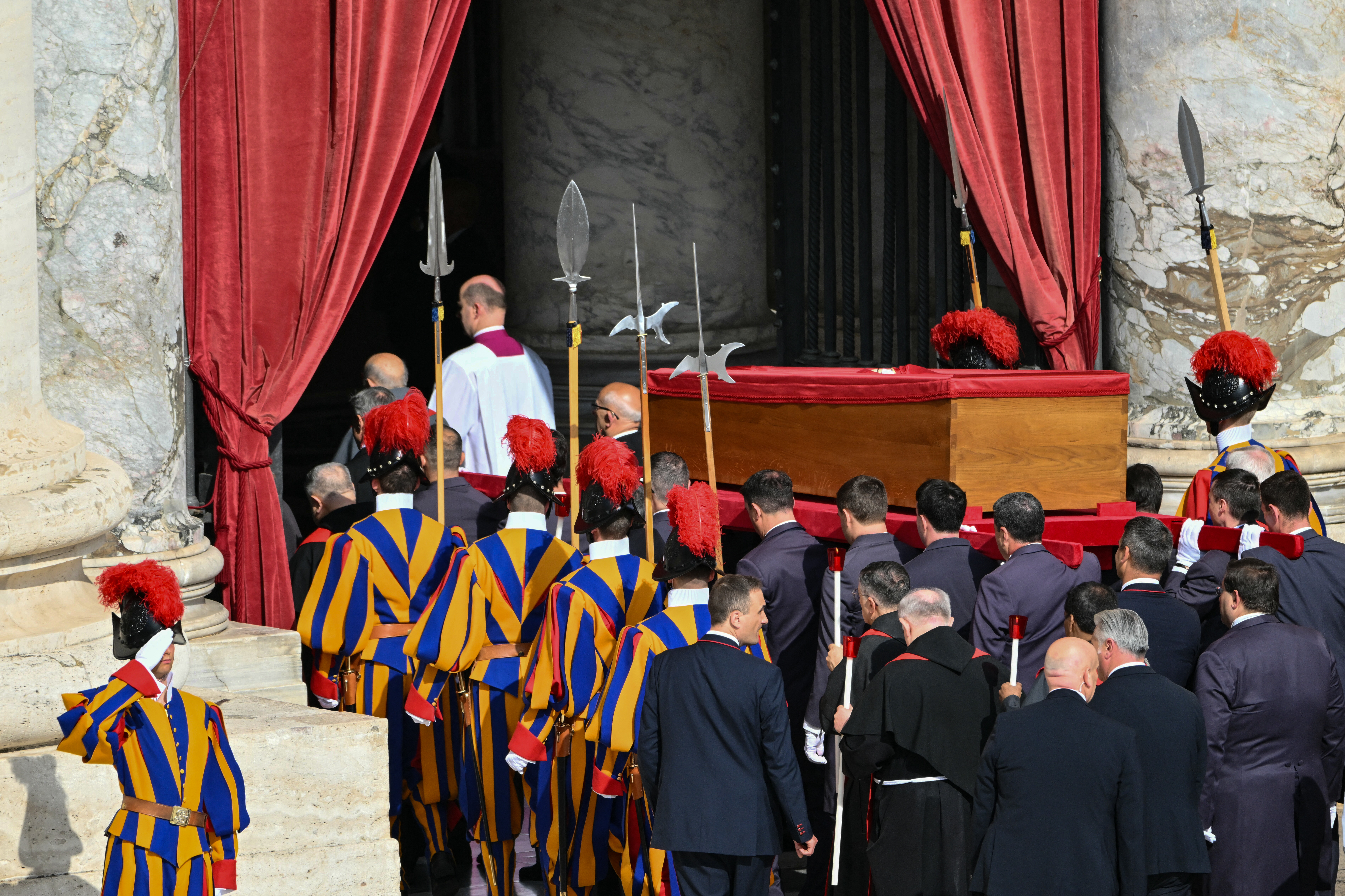 Pallbearers, next to Swiss Guards, carry the coffin of the late Pope Francis as it is transported from the chapel of Santa Marta to St Peter's Basilica, following the Pope's death, in the Vatican on April 23, 2025. The Pope died of a stroke, the Vatican announced hours after the death on April 21, 2025, of the 88-year-old reformer who inspired devotion but riled traditionalists during 12 years leading the Catholic Church. (Photo by Alberto PIZZOLI / AFP)