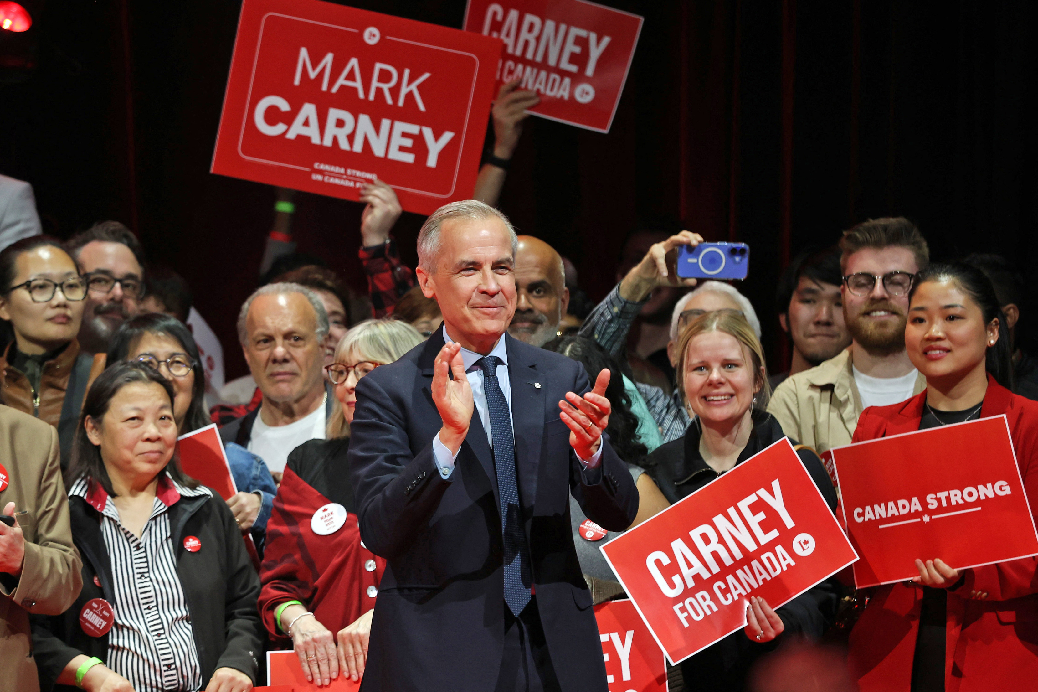 Canada's Prime Minister and Liberal Party leader Mark Carney applauds at a victory party.