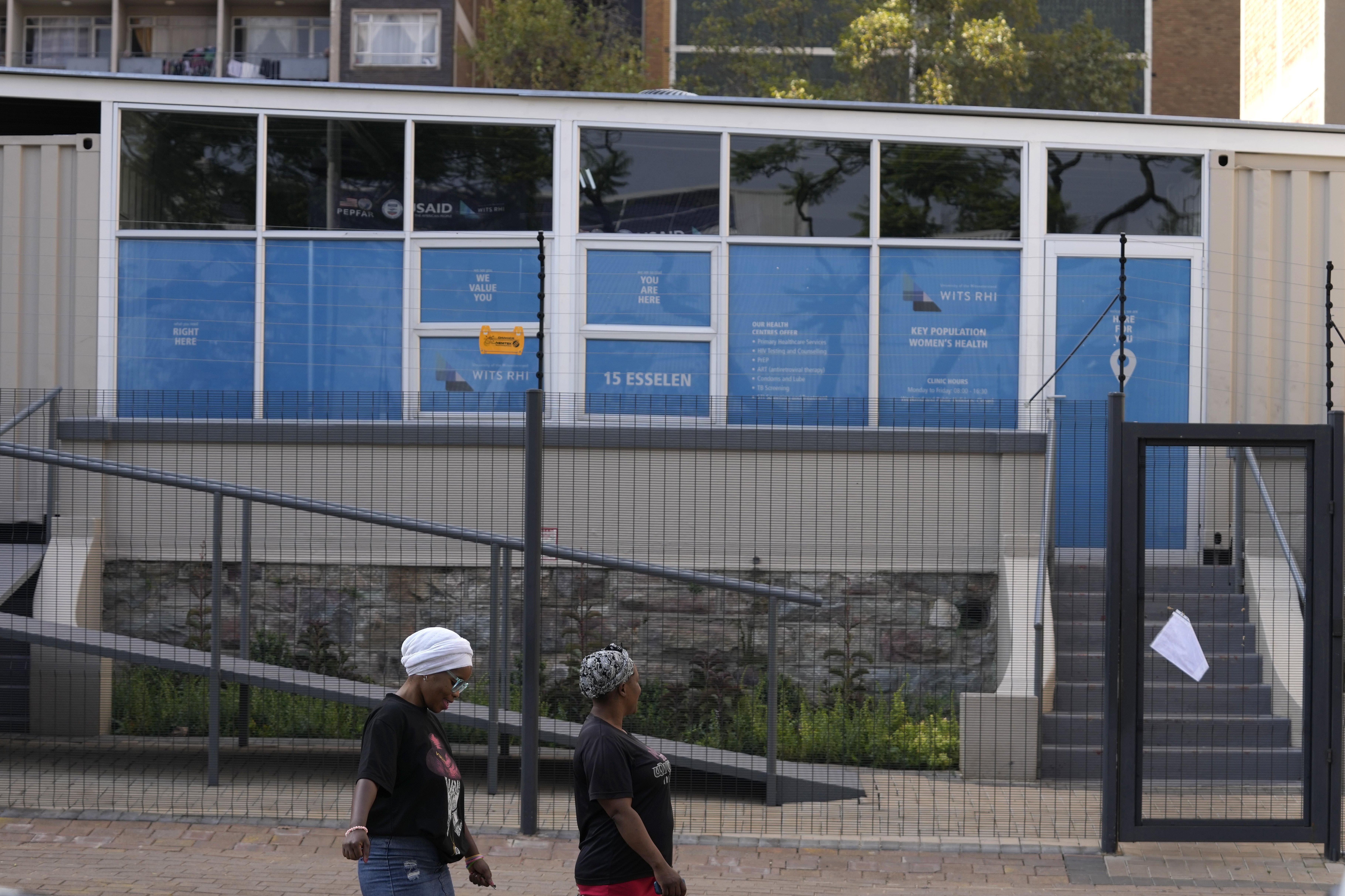 Women walk past a closed clinic.