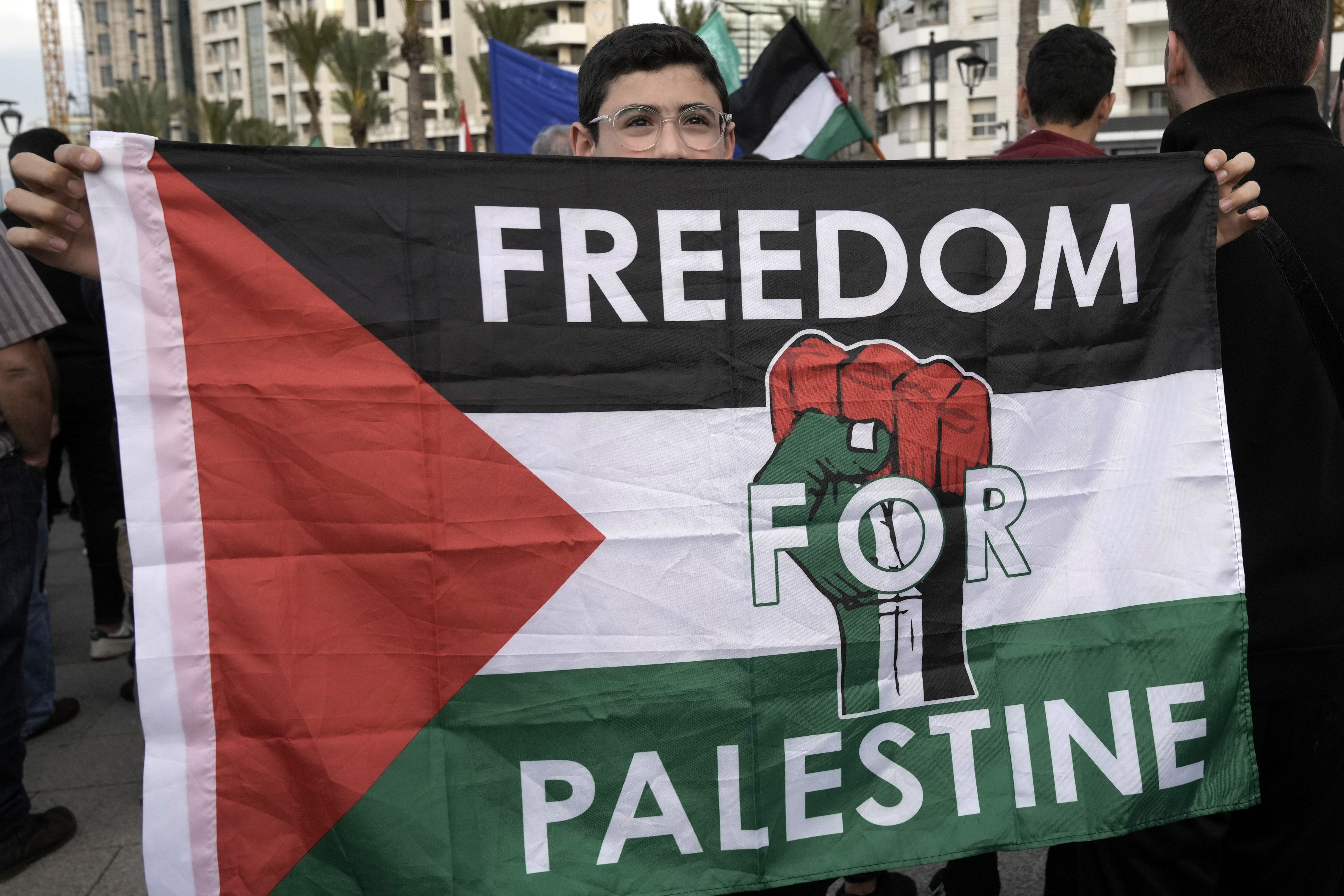 A young holds a Palestinian flag with a slogan written on it during a protest to condemn Israel's military operations in Gaza Strip, on Beirut's corniche, Lebanon, Monday, April 7, 2025. (AP Photo/Bilal Hussein)