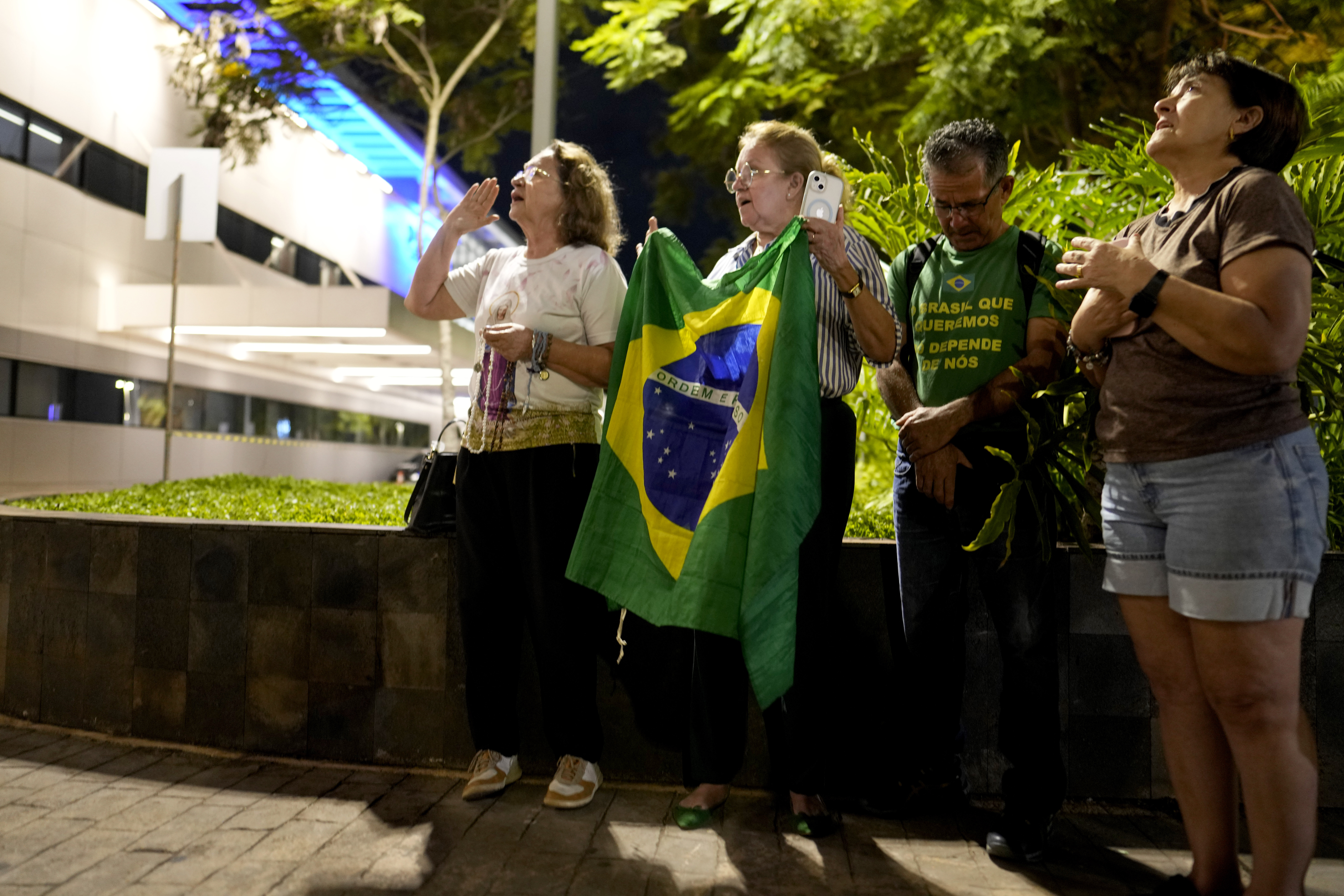 Supporters with a Brazilian flag pray for Bolsonaro outside a hospital