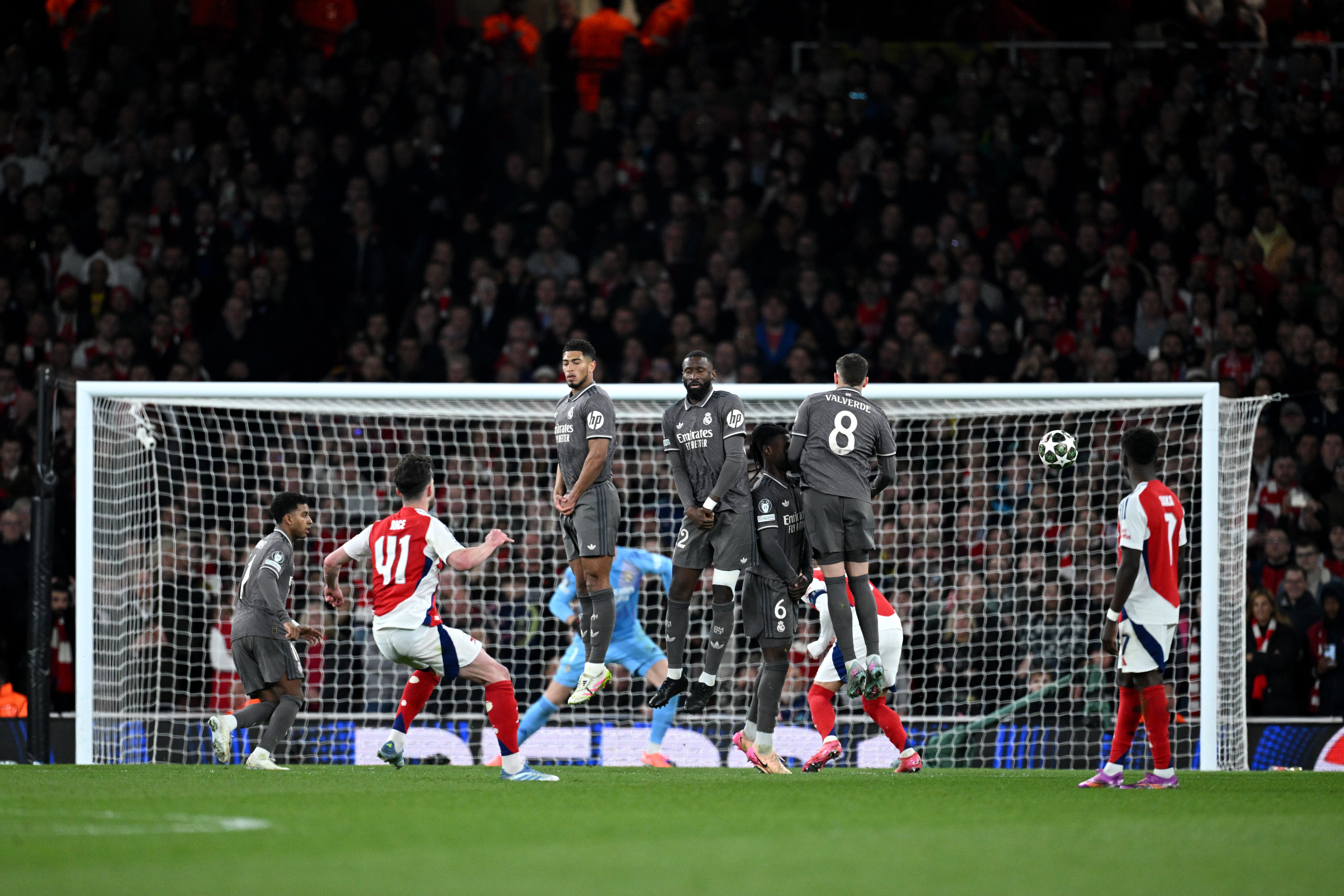 LONDON, ENGLAND - APRIL 08: Declan Rice of Arsenal scores his team's first goal from a free kick as Jude Bellingham, Antonio Ruediger, Eduardo Camavinga and Federico Valverde of Real Madrid jump in a defensive wall during the UEFA Champions League 2024/25 Quarter Final First Leg match between Arsenal FC and Real Madrid C.F. at Emirates Stadium on April 08, 2025 in London, England. (Photo by Justin Setterfield/Getty Images)