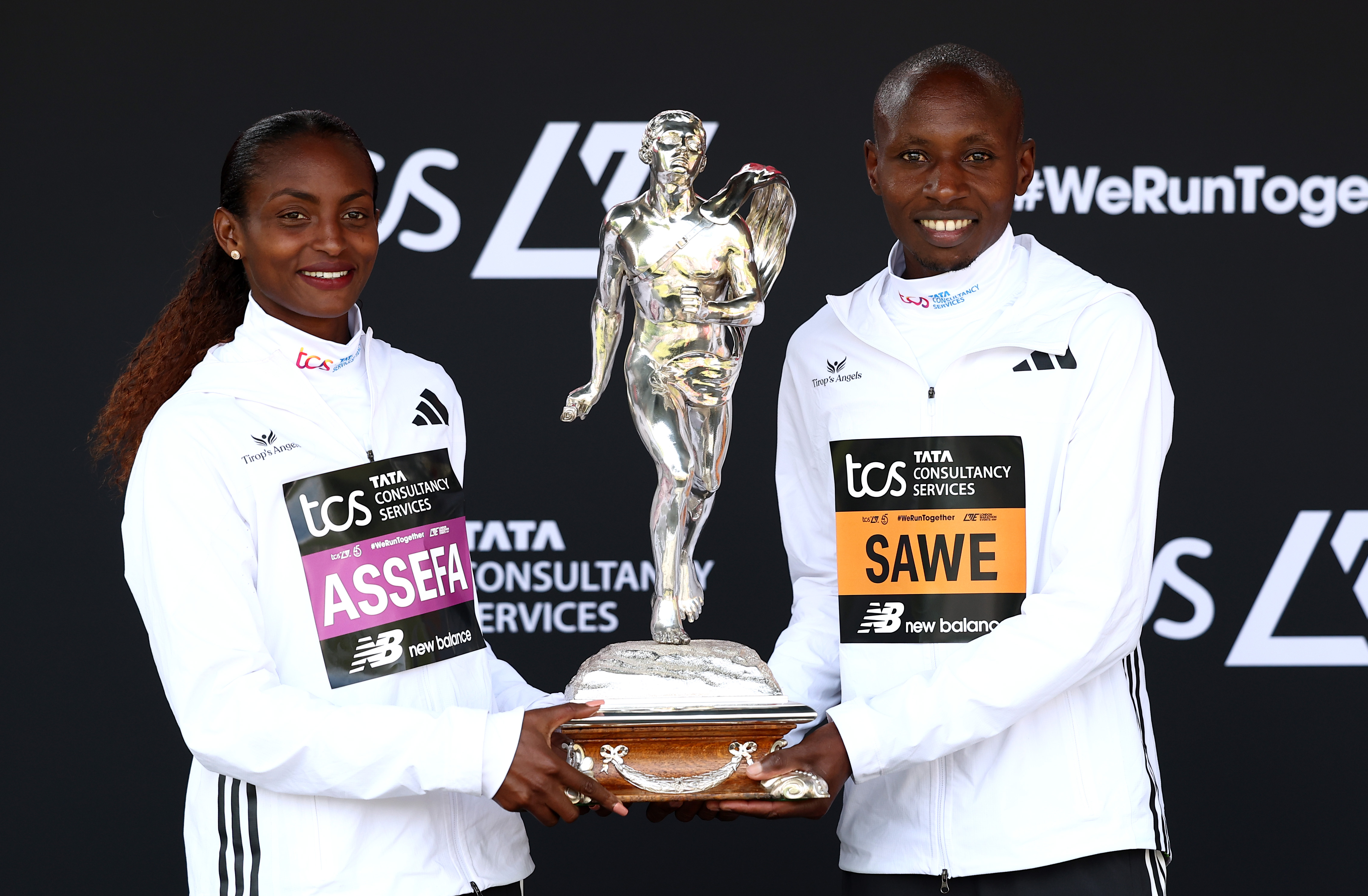 Tigst Assefa and Sebastian Sawe hold trophy.