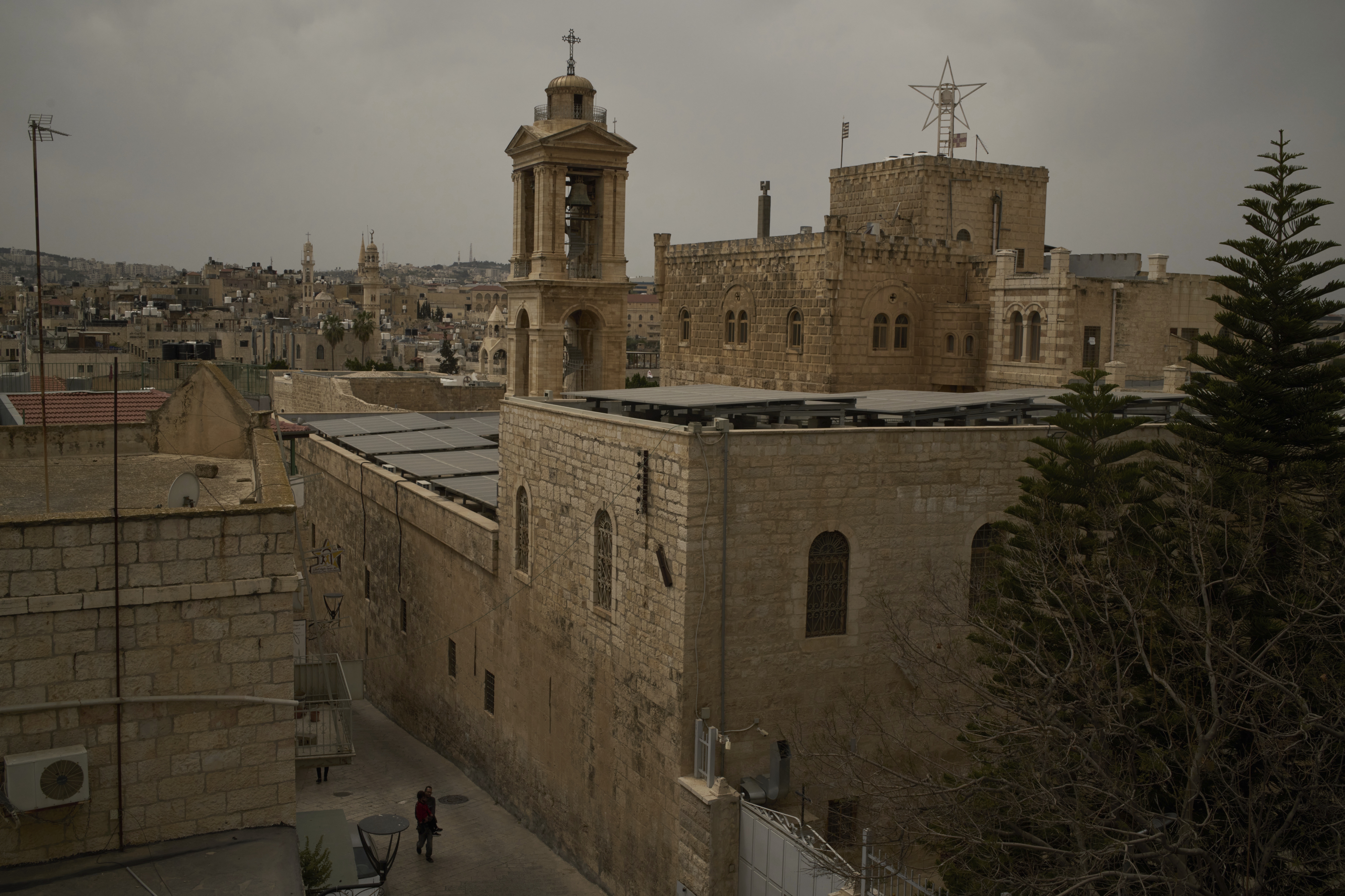 A man carries a child on a street near the Church of the Nativity, traditionally believed to be the birthplace of Jesus, in the West Bank city of Bethlehem on Wednesday, April 9, 2025. (AP Photo/Leo Correa)