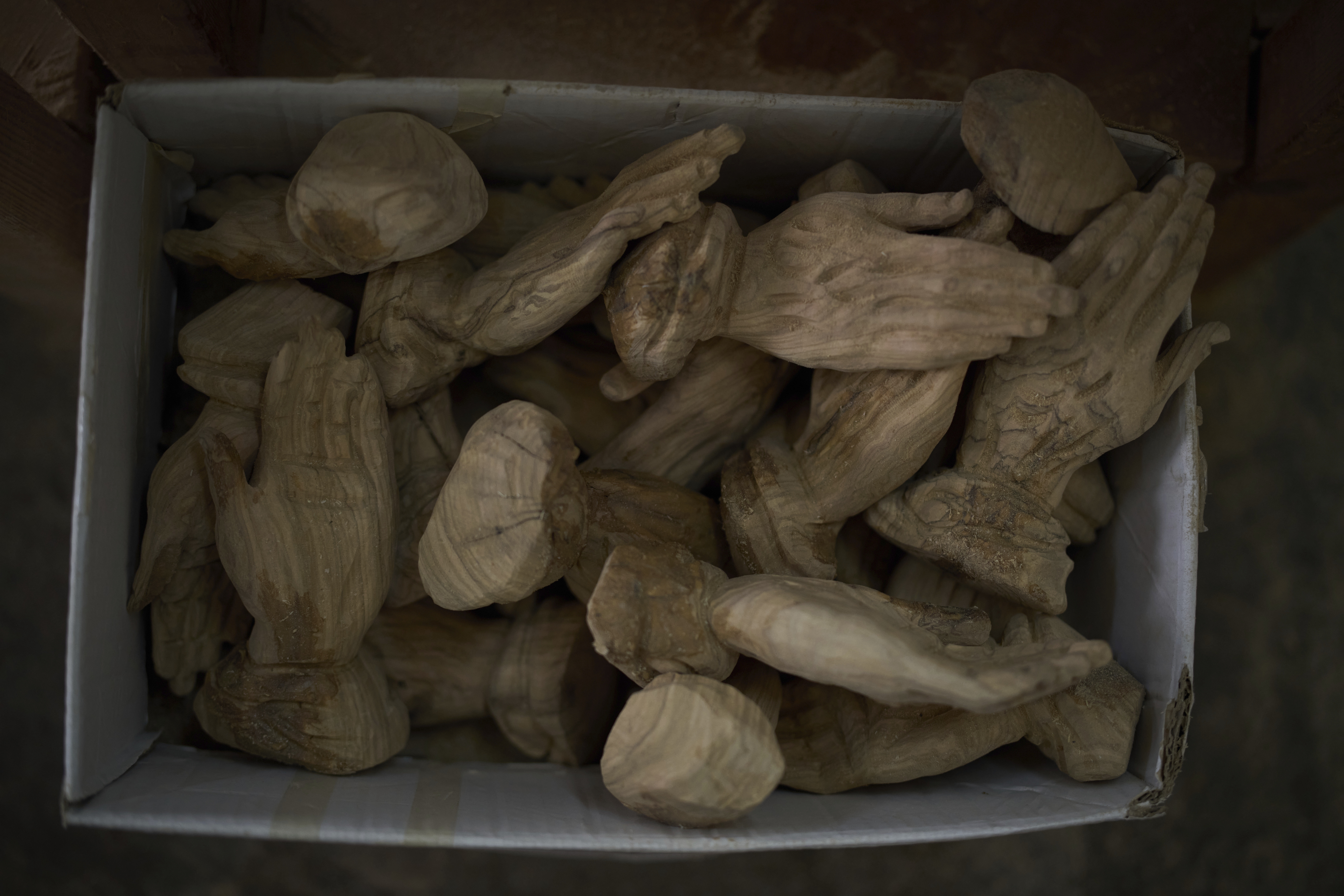 Sculptures depicting hands of olive wood are placed in a box at the Zacharia family workshop in the West Bank city of Bethlehem, Tuesday, April 8, 2025. (AP Photo/Leo Correa)