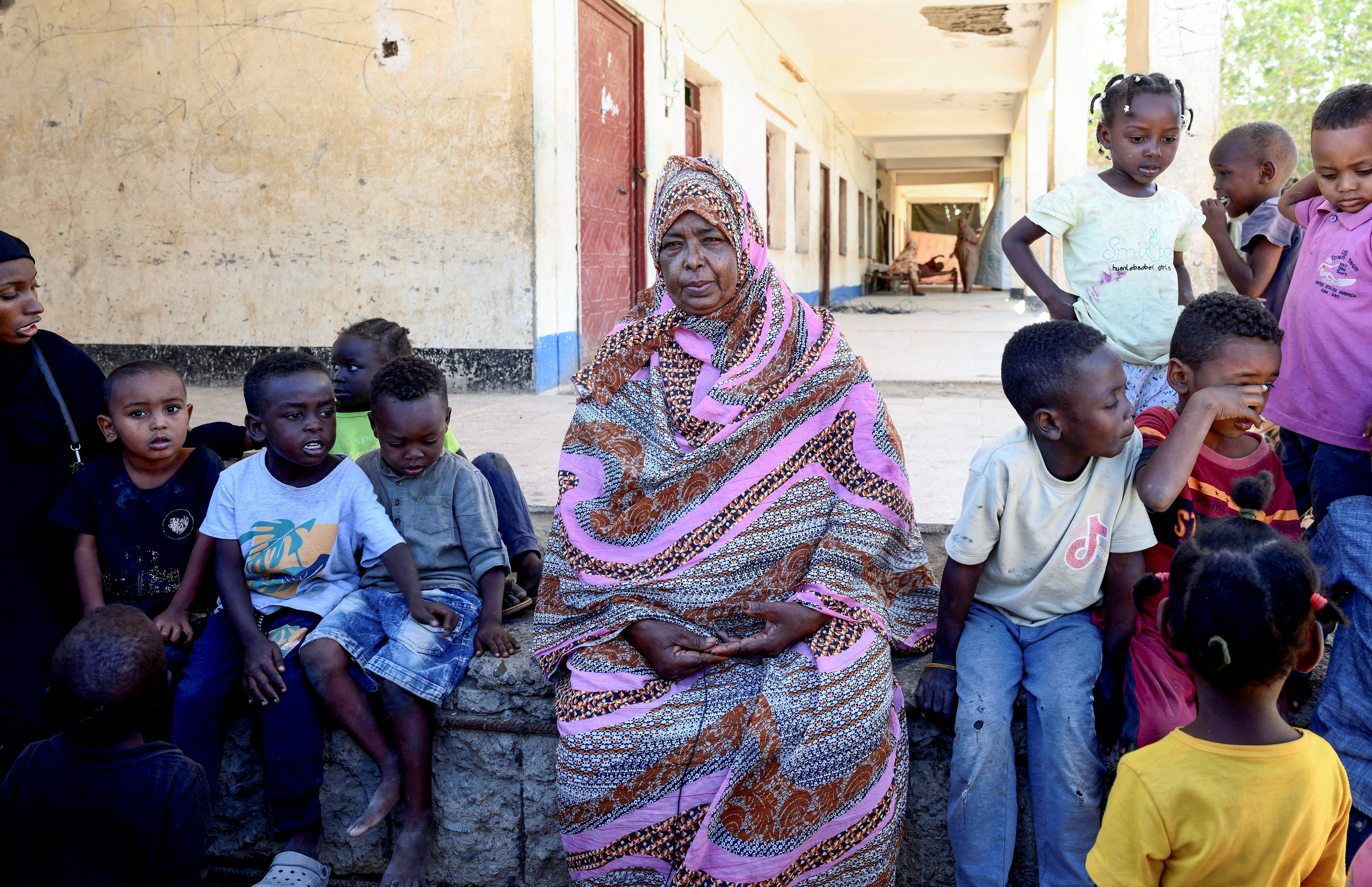 A displaced Sudanese woman sits next to children at "Abdallah Nagi" shelter camp.
