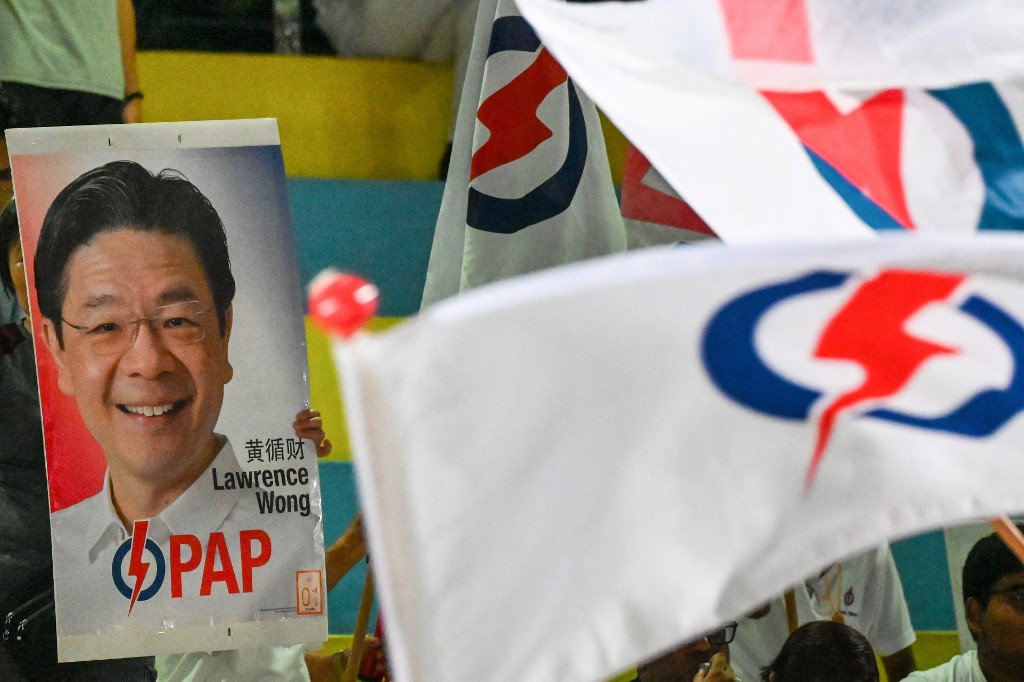 A poster featuring Singapore's Prime Minister and secretary-general of the ruling People's Action Party (PAP) Lawrence Wong is displayed as supporters cheer on the party while awaiting the vote count for the general election in Singapore on May 3, 2025. [Roslan Rahman/ AFP]
