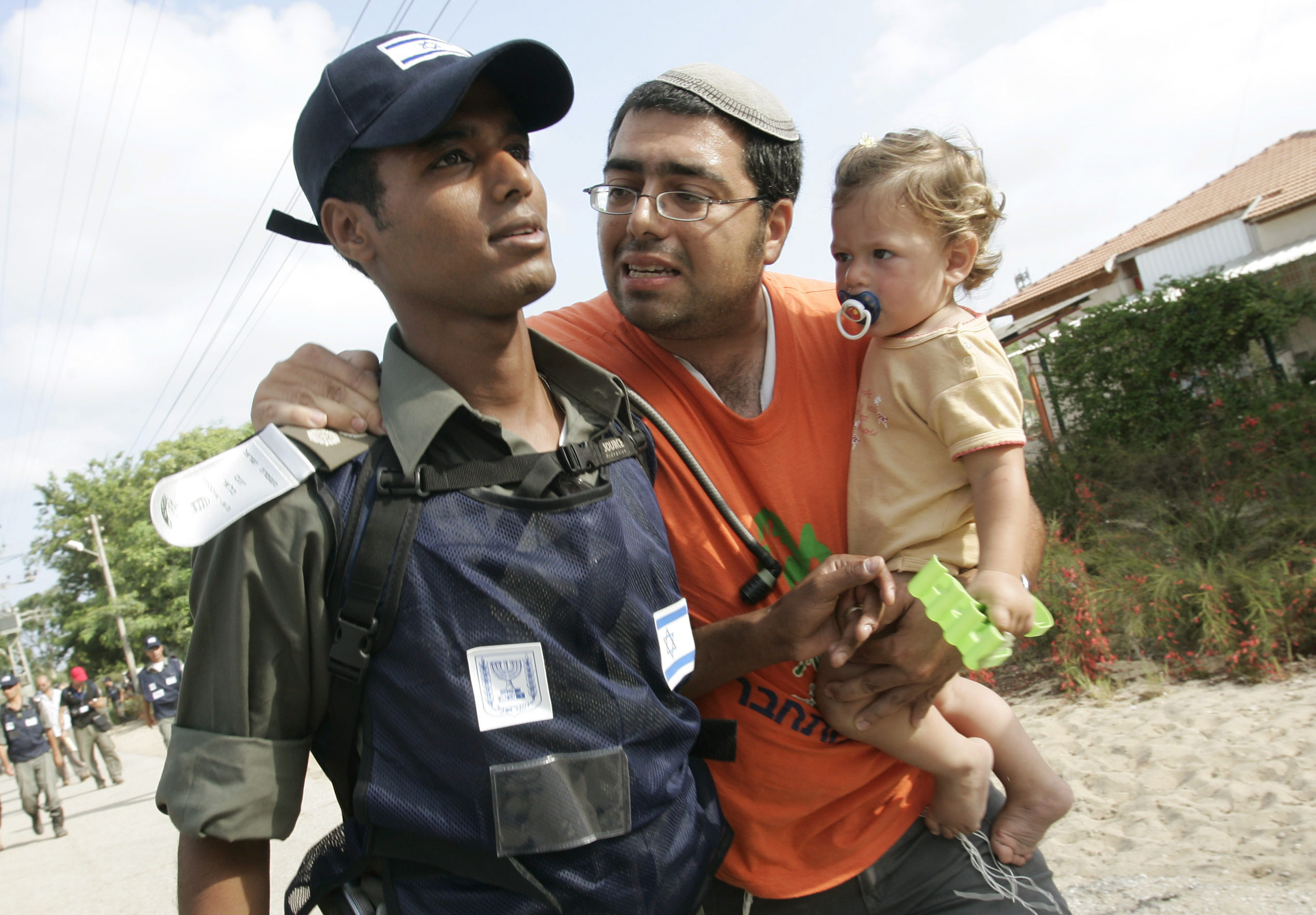 A settler carrying his child tries to convince an Israeli policemen to let them stay in the Jewish settlement of Ganei Tal, southern Gaza Strip. A settler carrying his child tries to convince an Israeli policemen to let them stay in the Jewish settlement of Ganei Tal, in the Gush Katif settlement bloc, in the southern Gaza Strip, August 17, 2005. Israeli troops began the forced evacuation on Wednesday of thousands of Jewish settlers gripped by rage and anguish over their eviction from the Gaza Strip after nearly four decades of occupation. REUTERS/Jerry Lampen