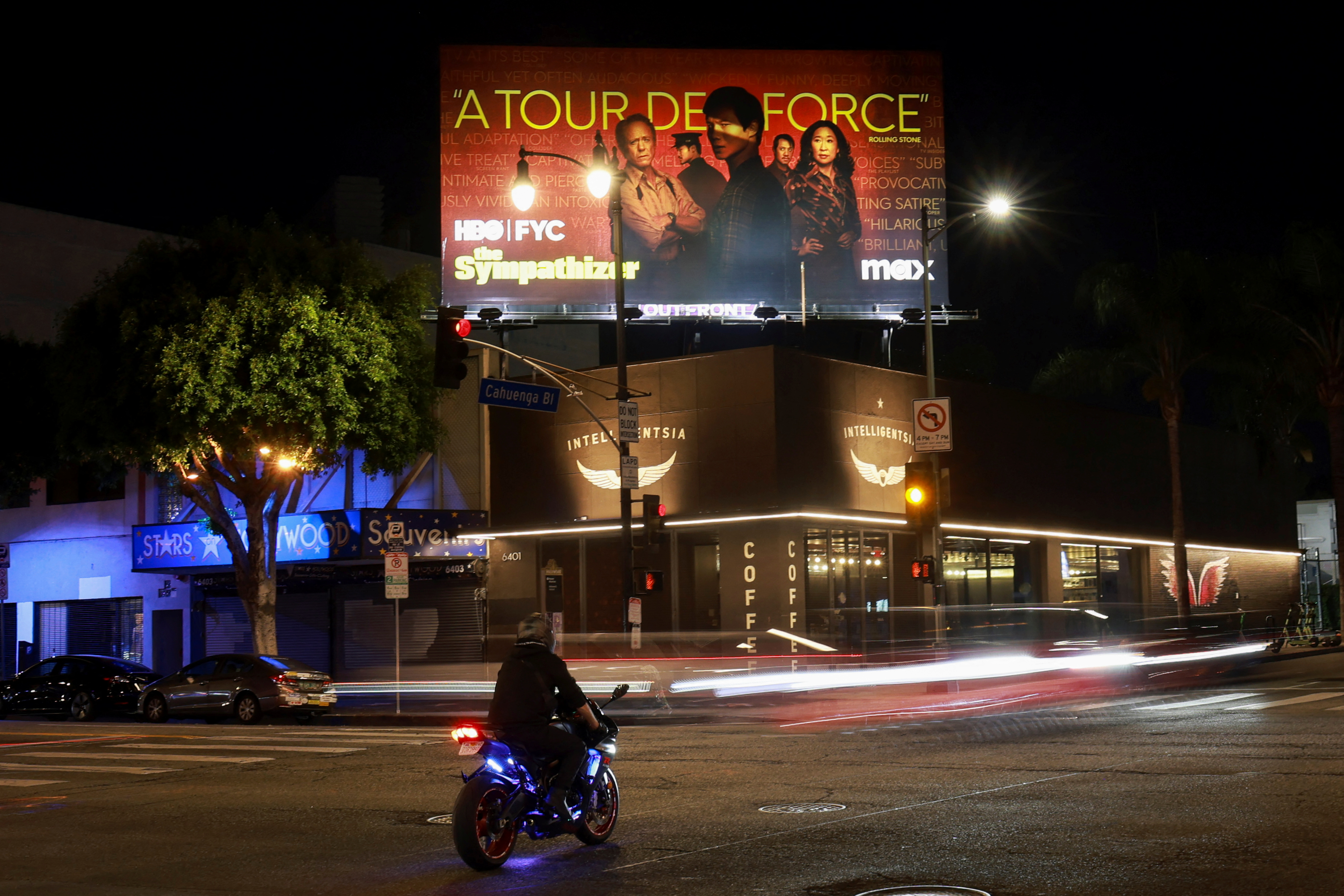 A billboard for "The Sympathizer" sits atop an Intelligentsia coffee shop at night in Los Angeles, as traffic passes on the street below.