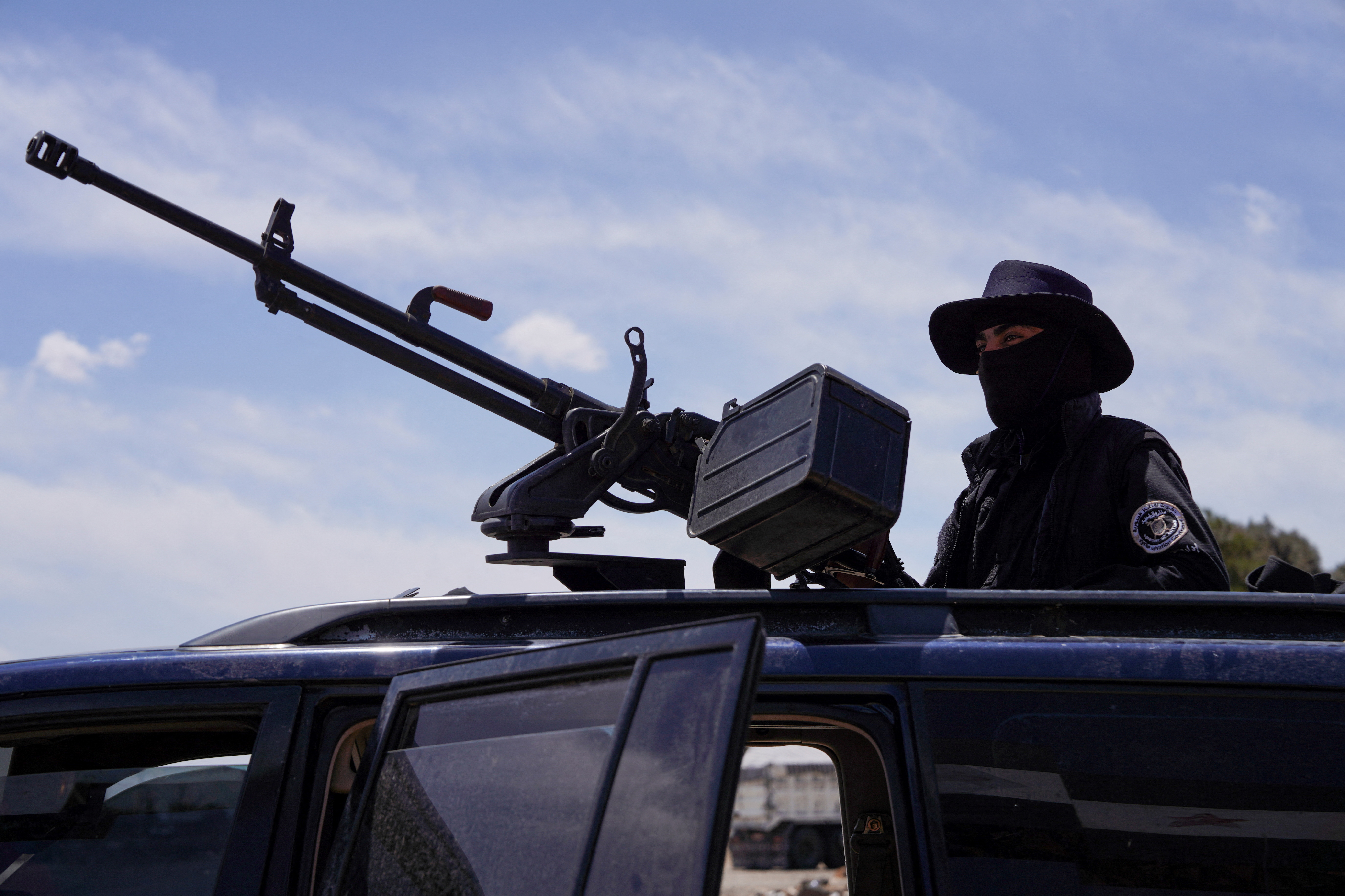 A member of Syrian security forces stands guard after being deployed in the village of Al-Soura al-Kubra, following clashes between Sunni Islamist militants and Druze fighters, in Sweida province, Syria, May 2, 2025. REUTERS/Karam Al-Masri