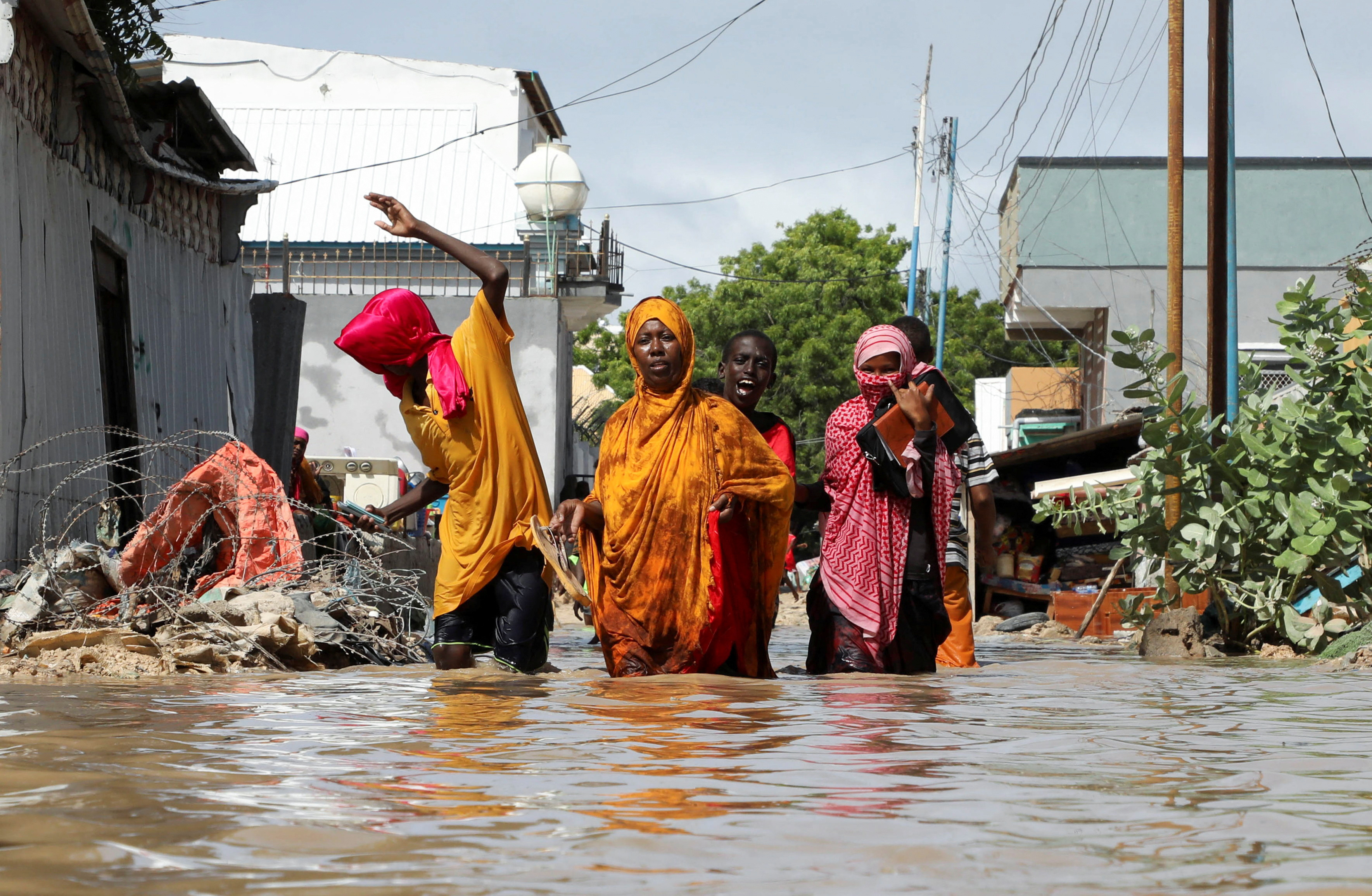 A Somali family wades through flood waters, as they flee after overnight rains destroyed their home
