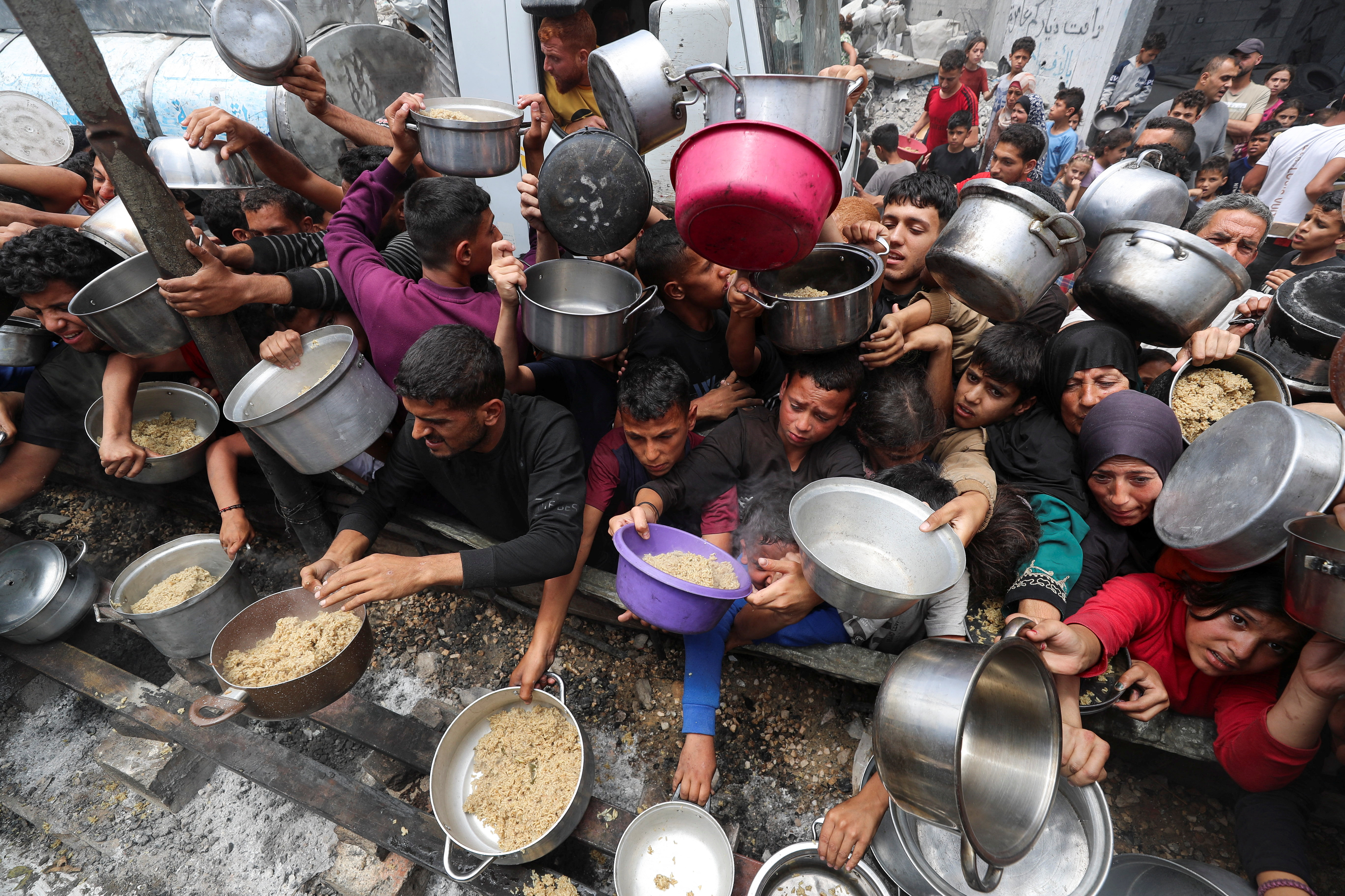Palestinians wait for food at a charity kitchen in Gaza's Jabalia