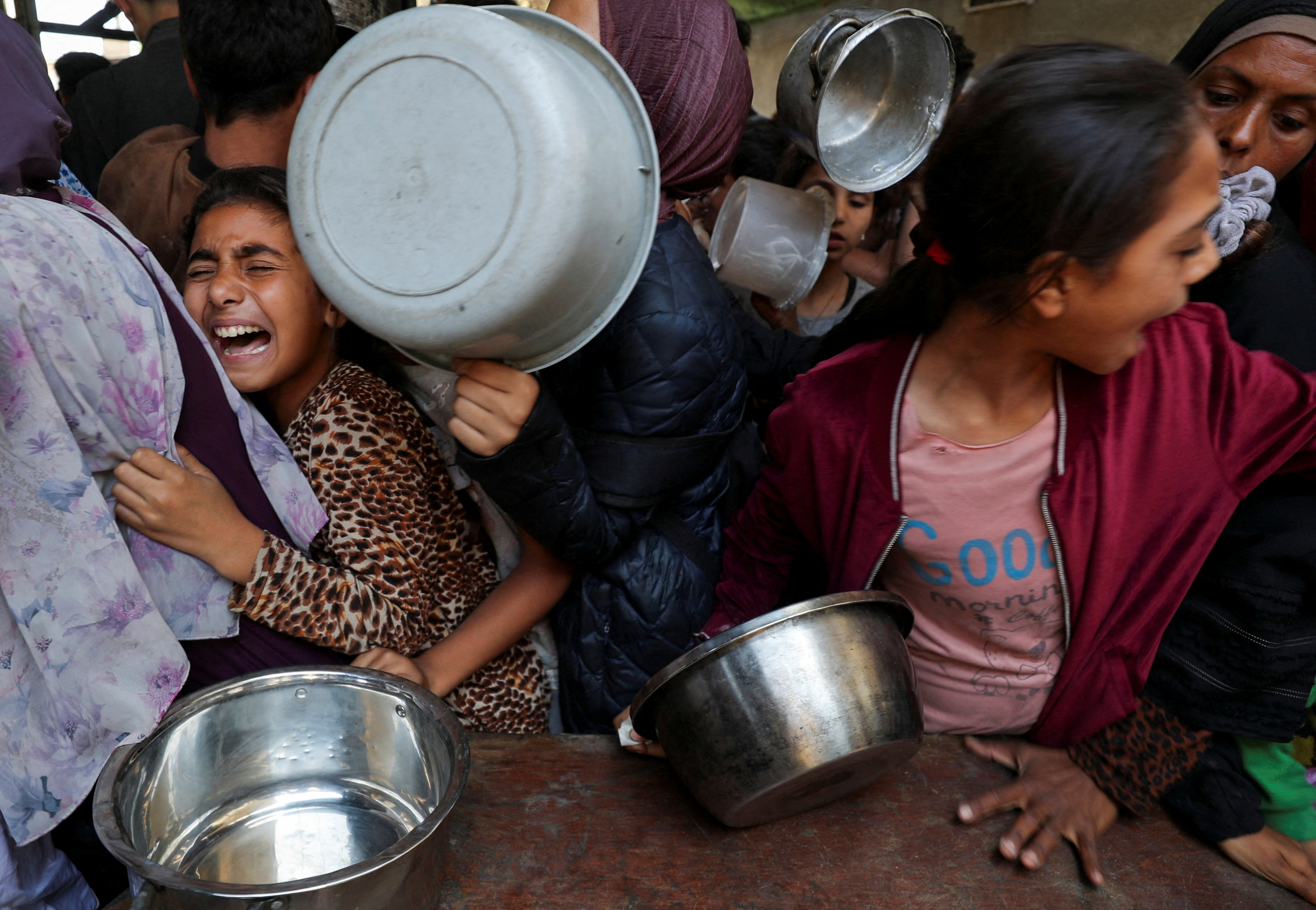 Palestinians wait to receive food cooked by a charity kitchen in Gaza City, May 21, 2025. [Mahmoud Issa/Reuters]