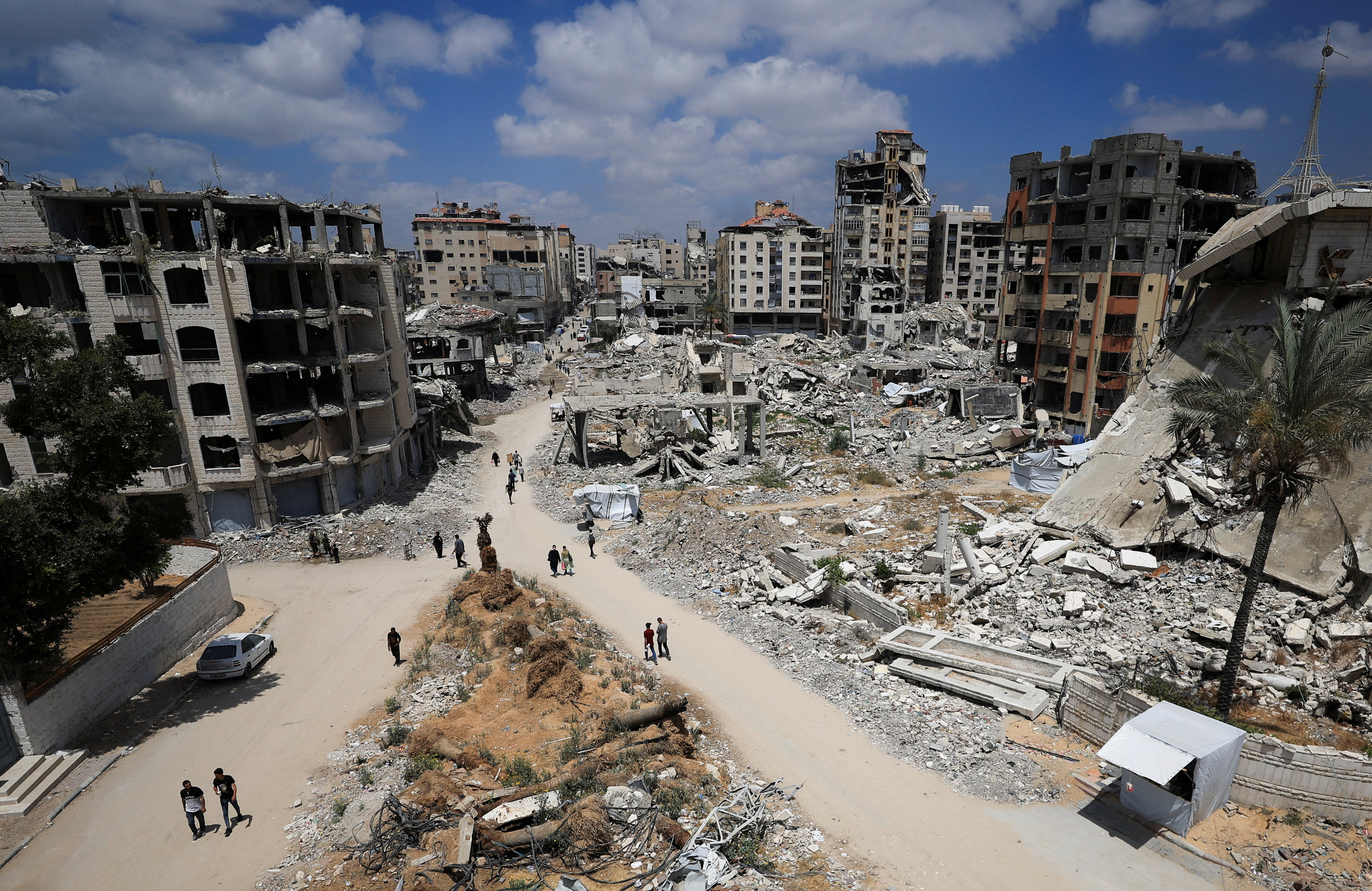 Palestinians walk near destroyed buildings in Gaza City