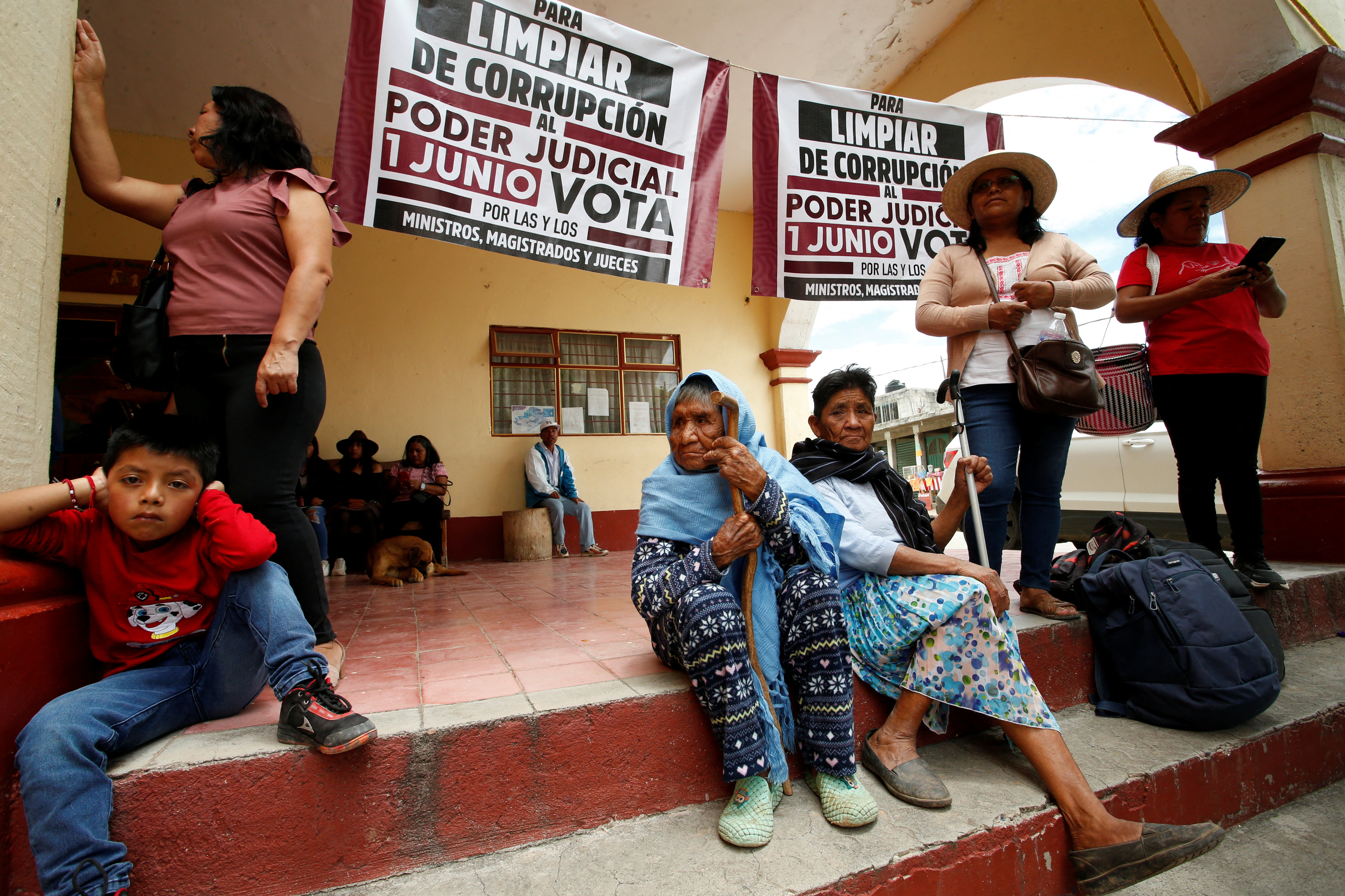 People sit inside on a pair of steps where a judicial candidate held a rally