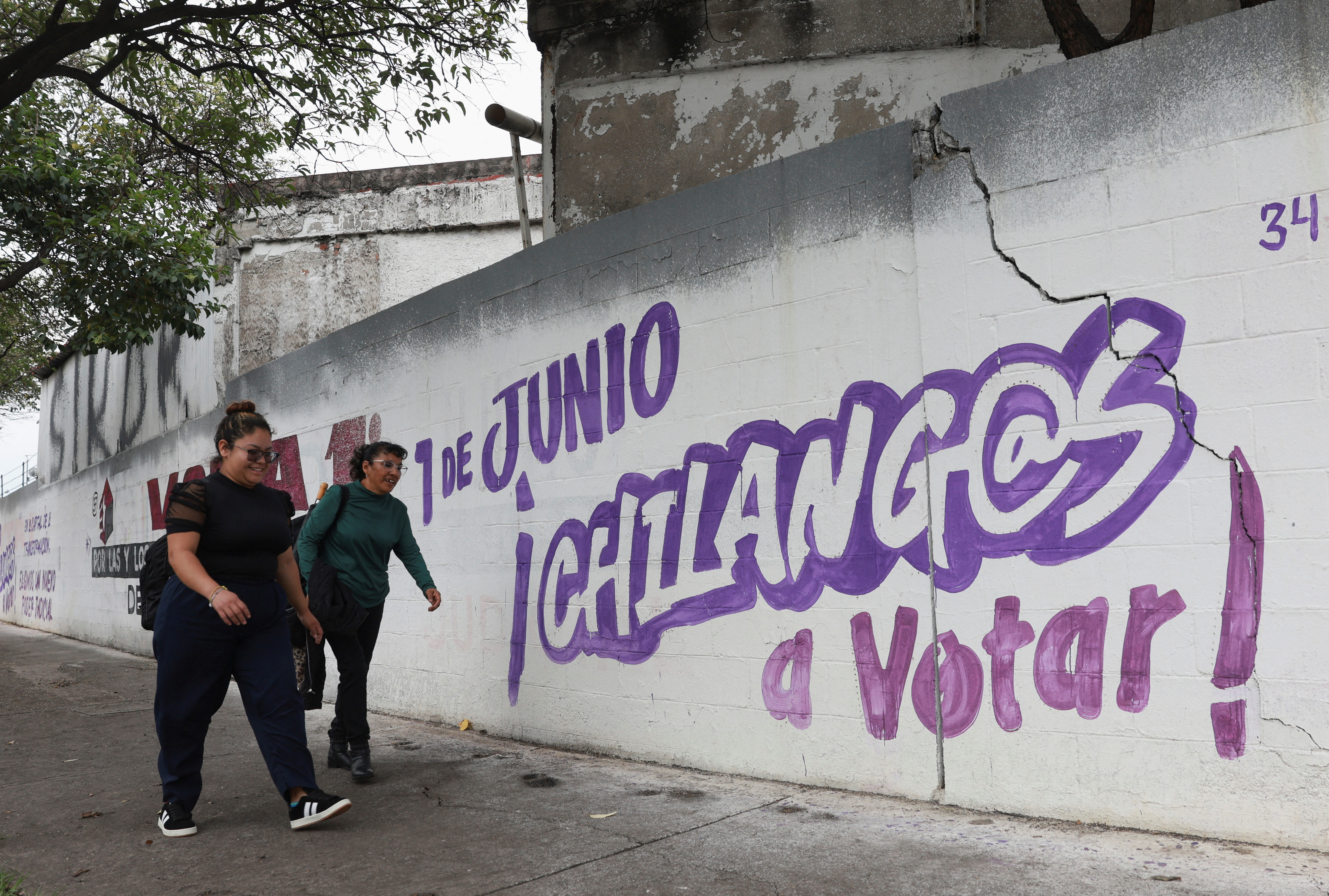 Graffiti on a wall next to a sidewalk advertises Mexico's judicial election