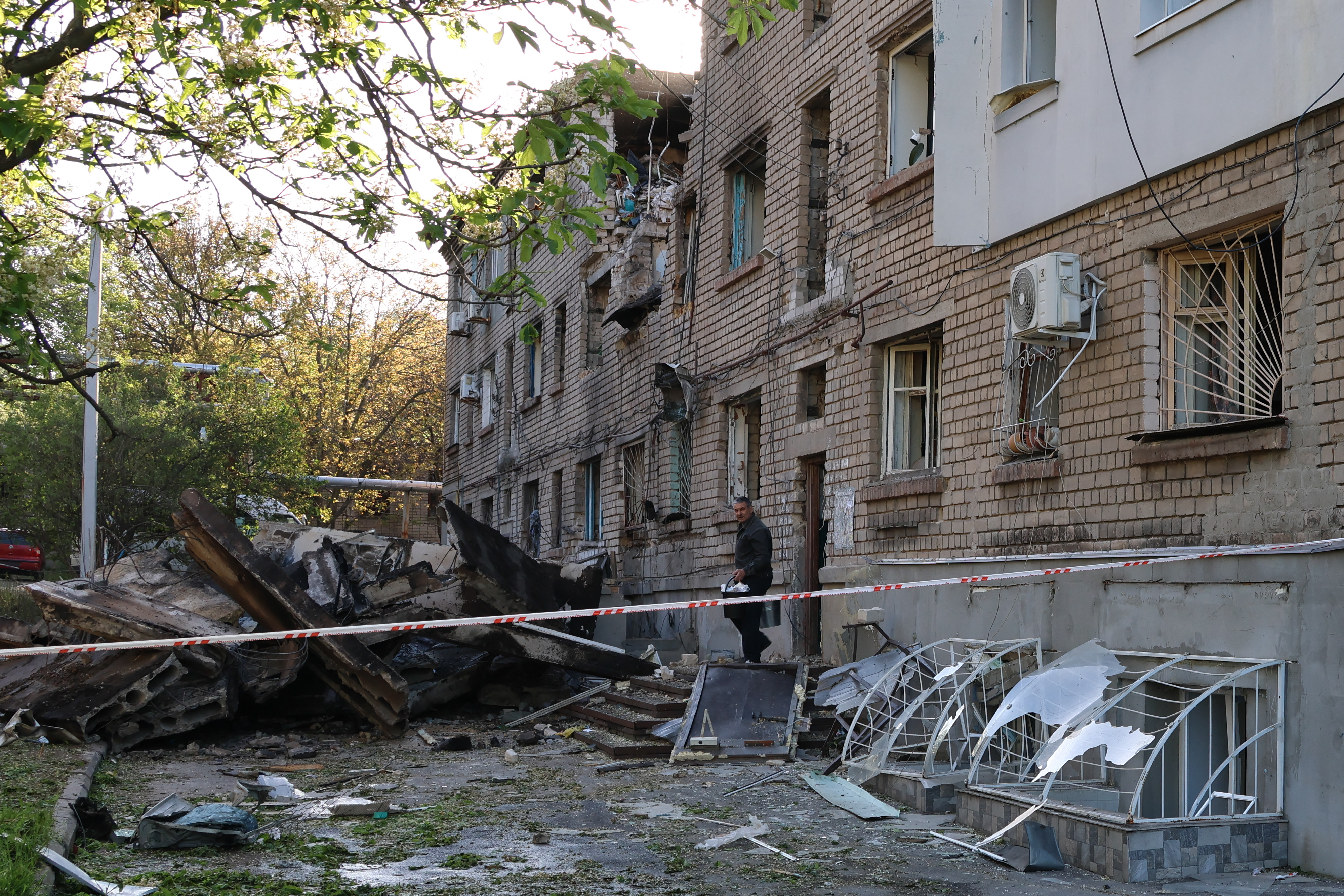 A resident takes his belongings out of a damaged residential building after a drone attack in Zaporizhzhia on May 2, 2025, amid the Russian invasion of Ukraine.