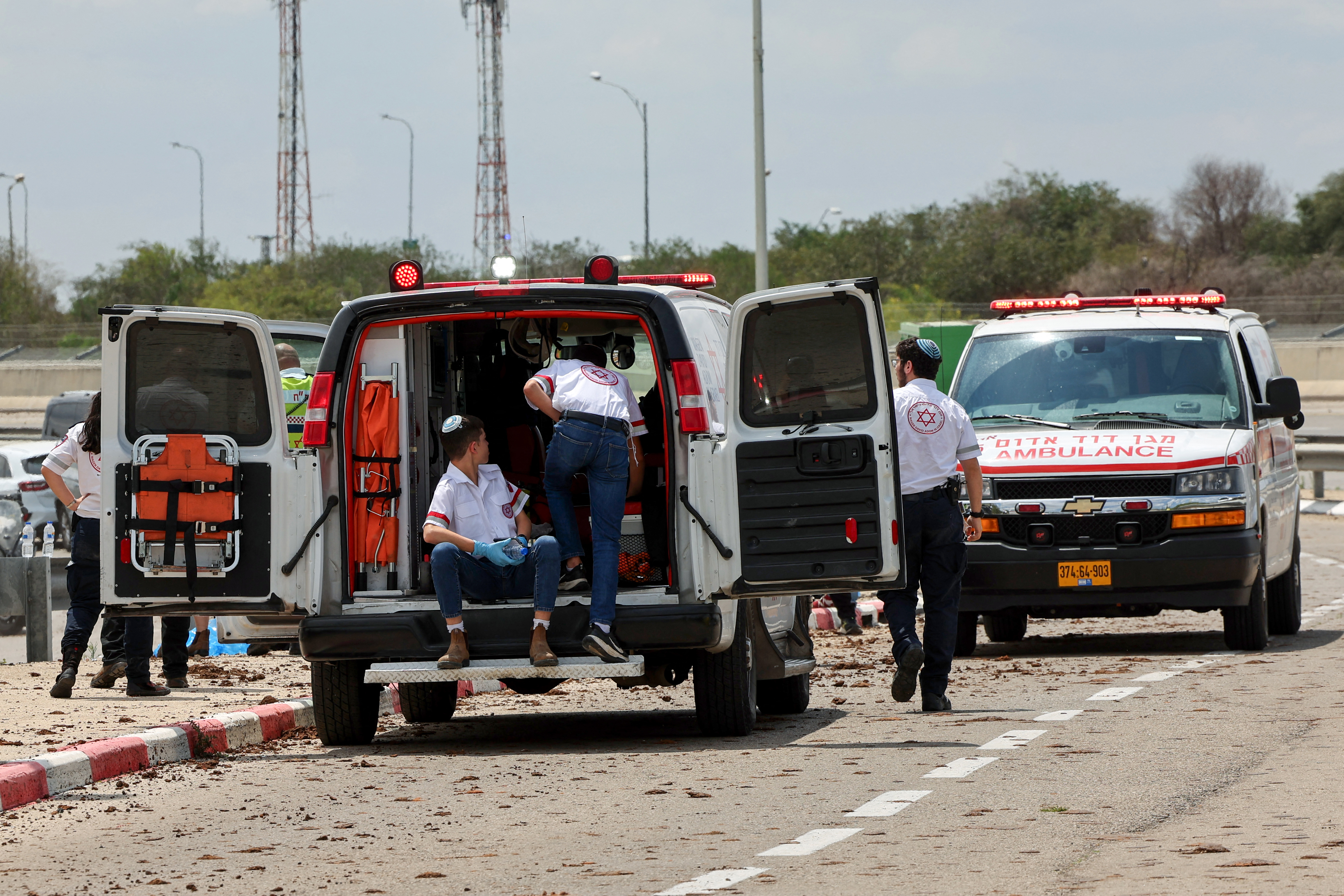 Israeli medical emergency services stand by on a mud-splattered road outside Israel's Ben Gurion airport