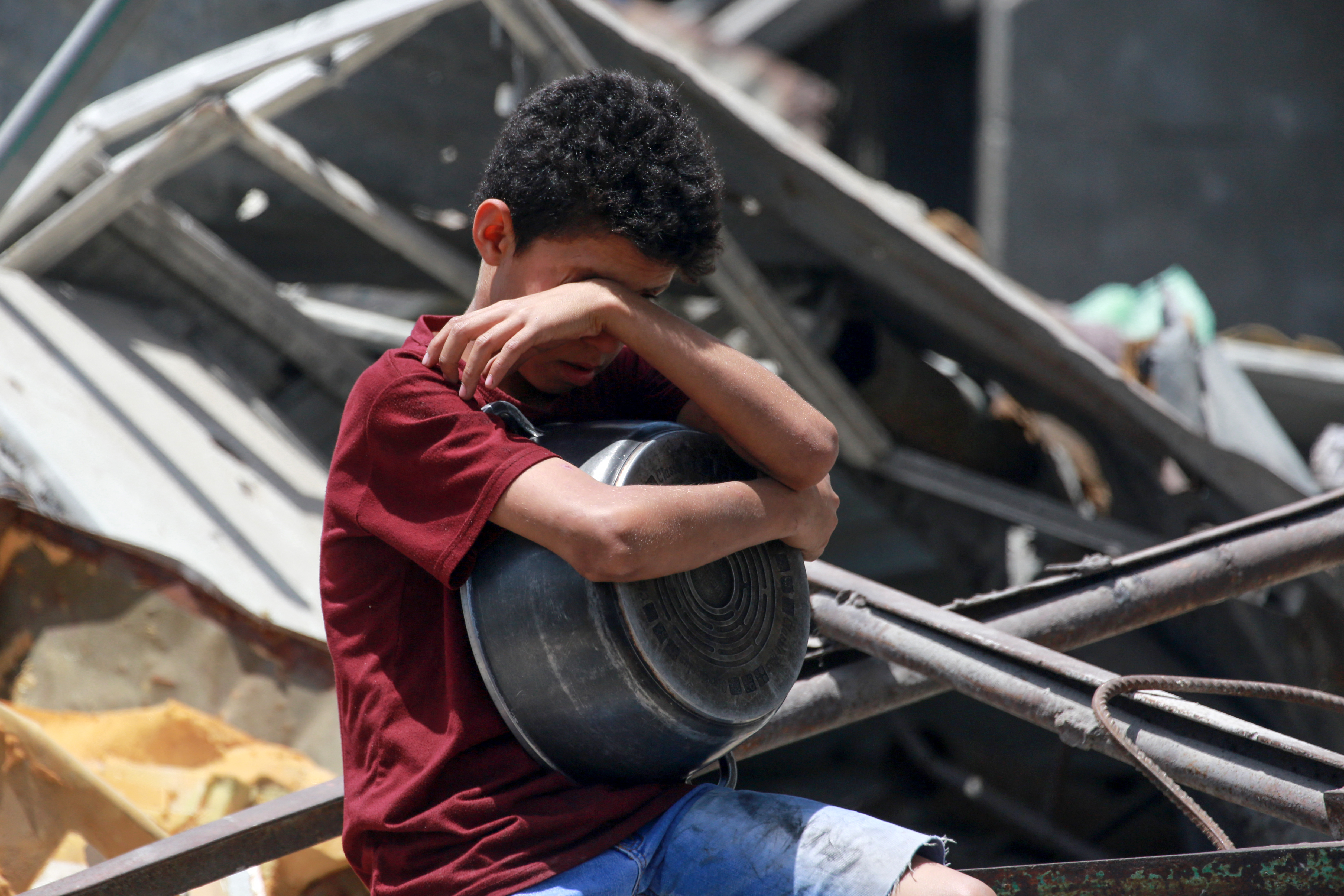 a child hugs an empty cooking pot and cries