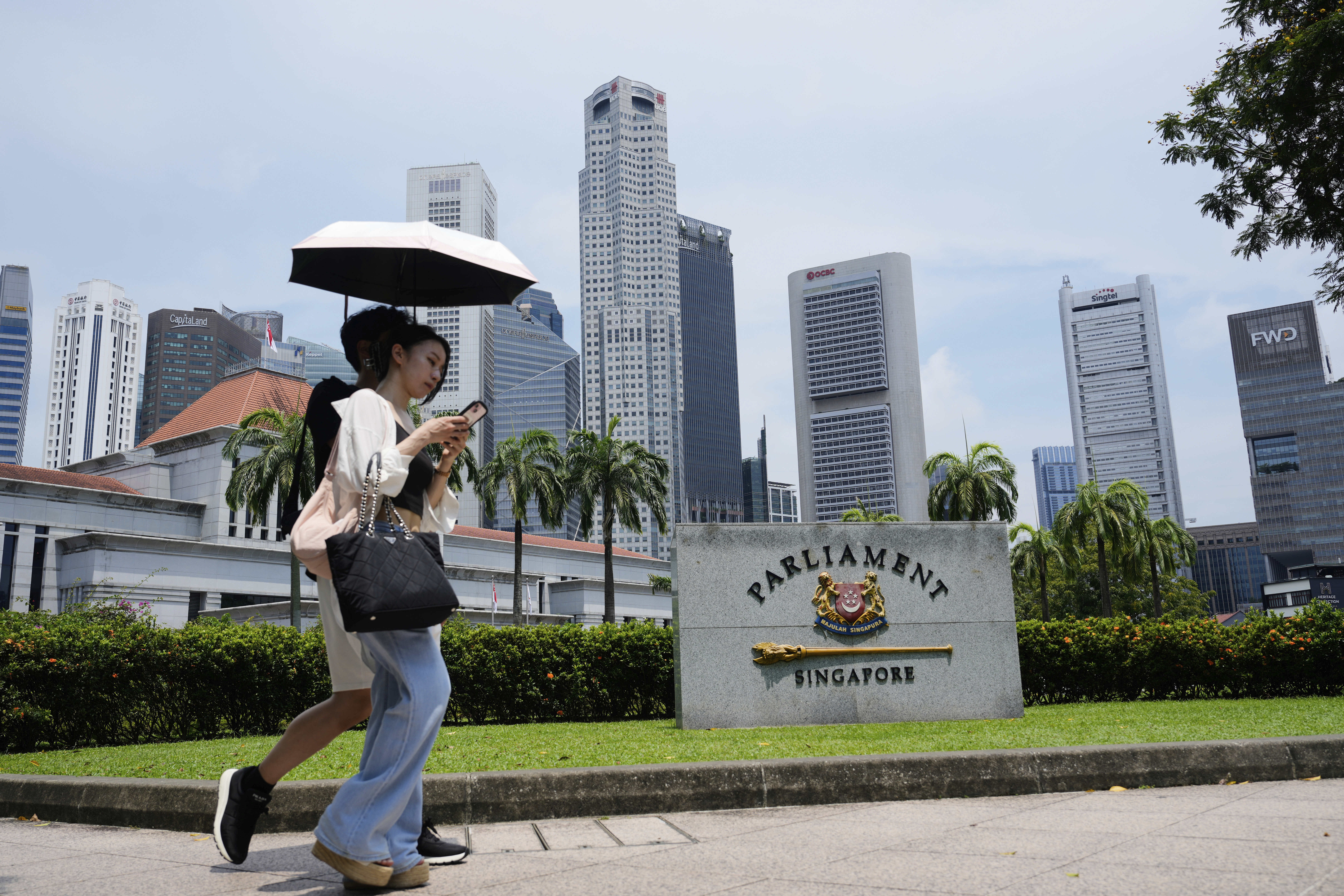 Pedestrians walk in front of the parliament building in Singapore, Friday, May 2, 2025. (AP Photo/Vincent Thian)