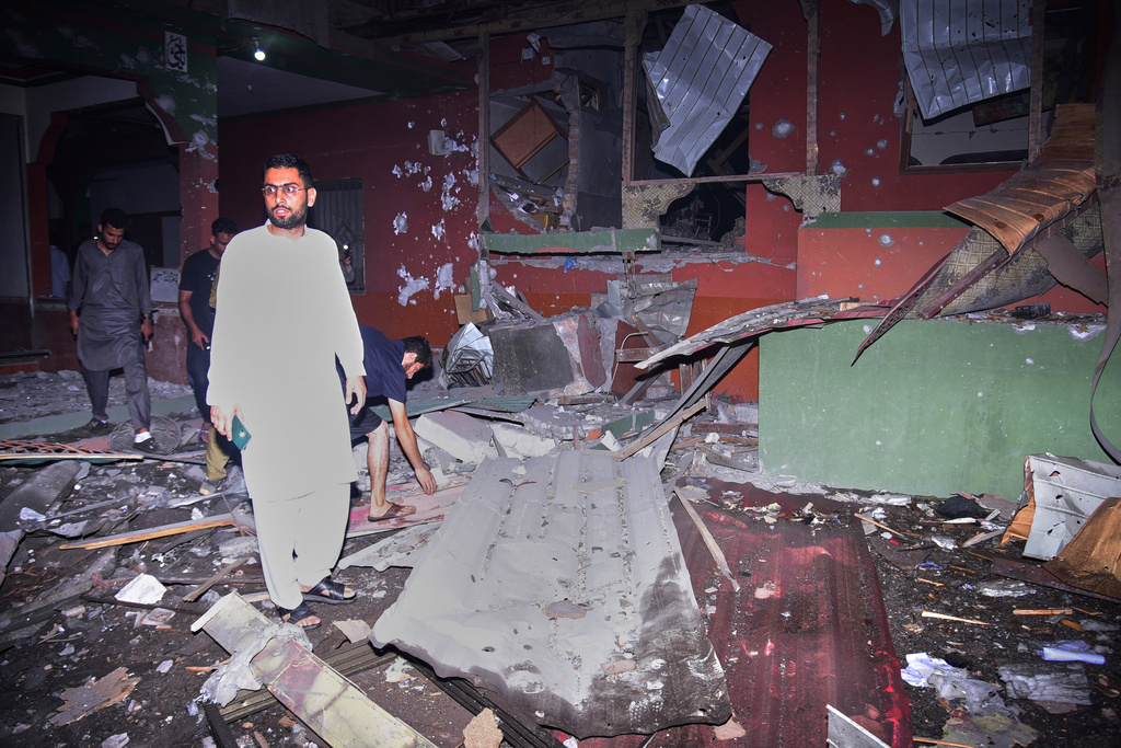 Local residents inspect building damaged in Muzaffarabad