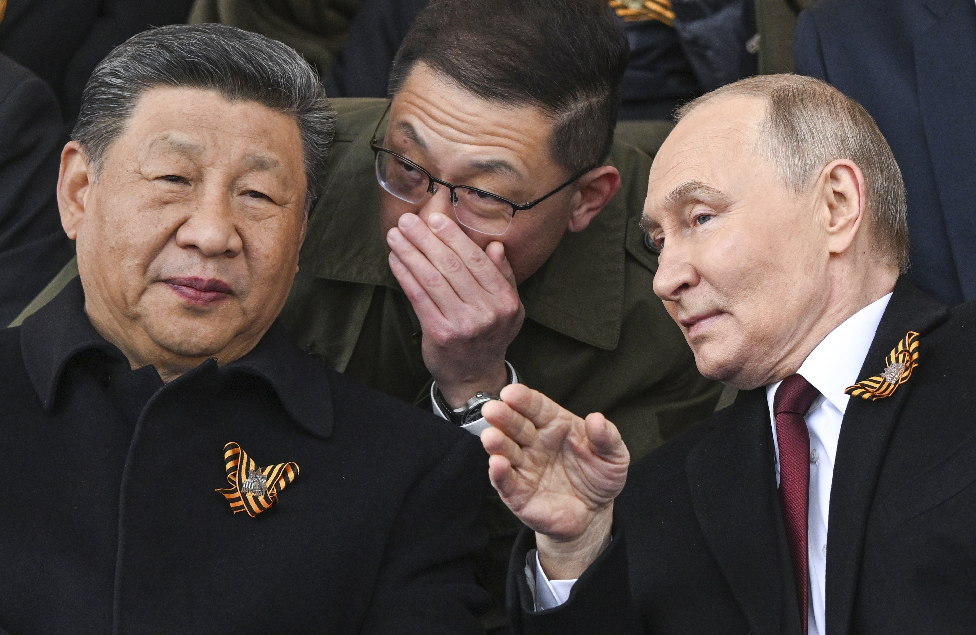 Russian President Vladimir Putin, right, and Chinese President Xi Jinping, left, talk as they watch the Victory Day military parade in Moscow, Russia