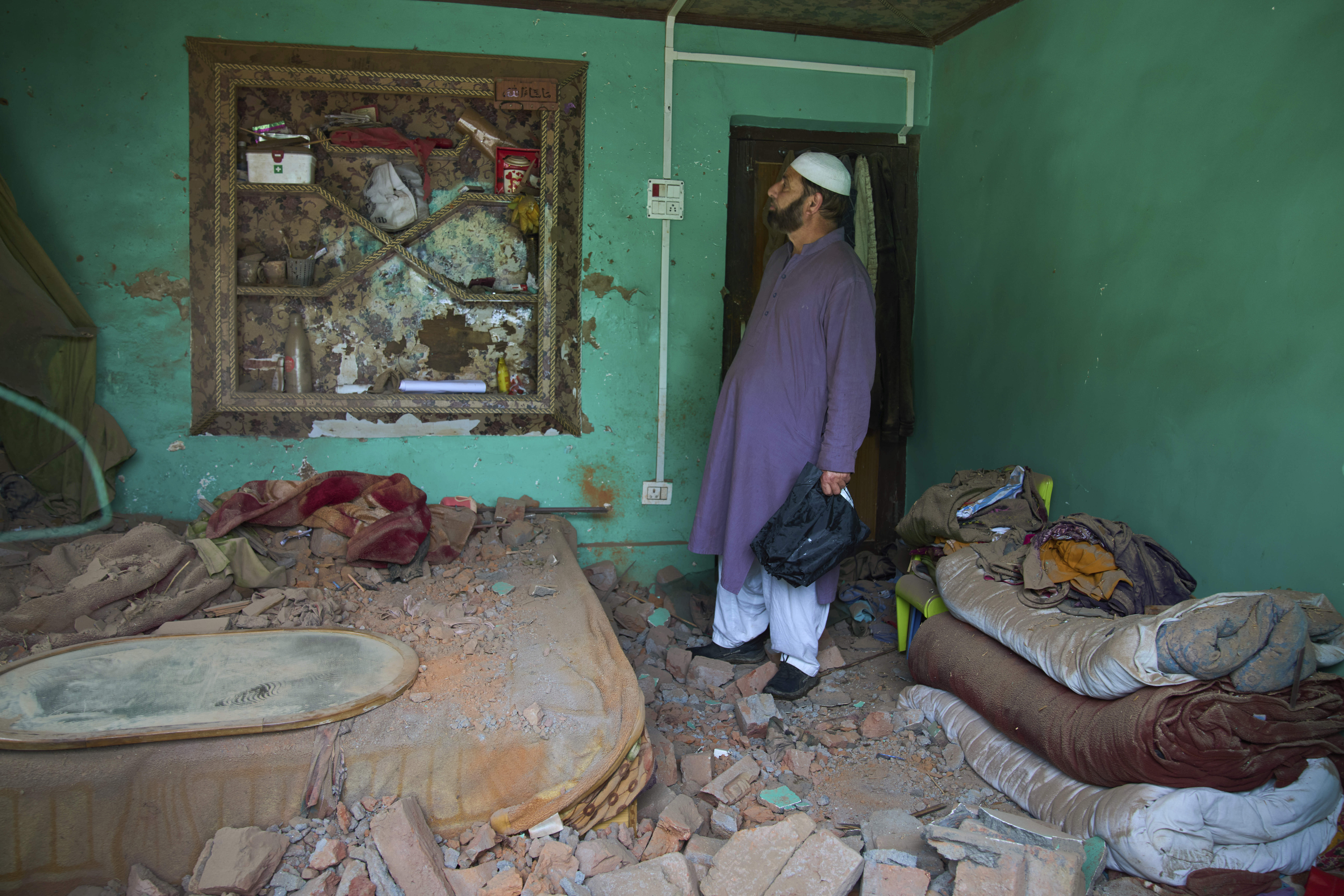 Kashmiri villager inspects his damaged house in Uri