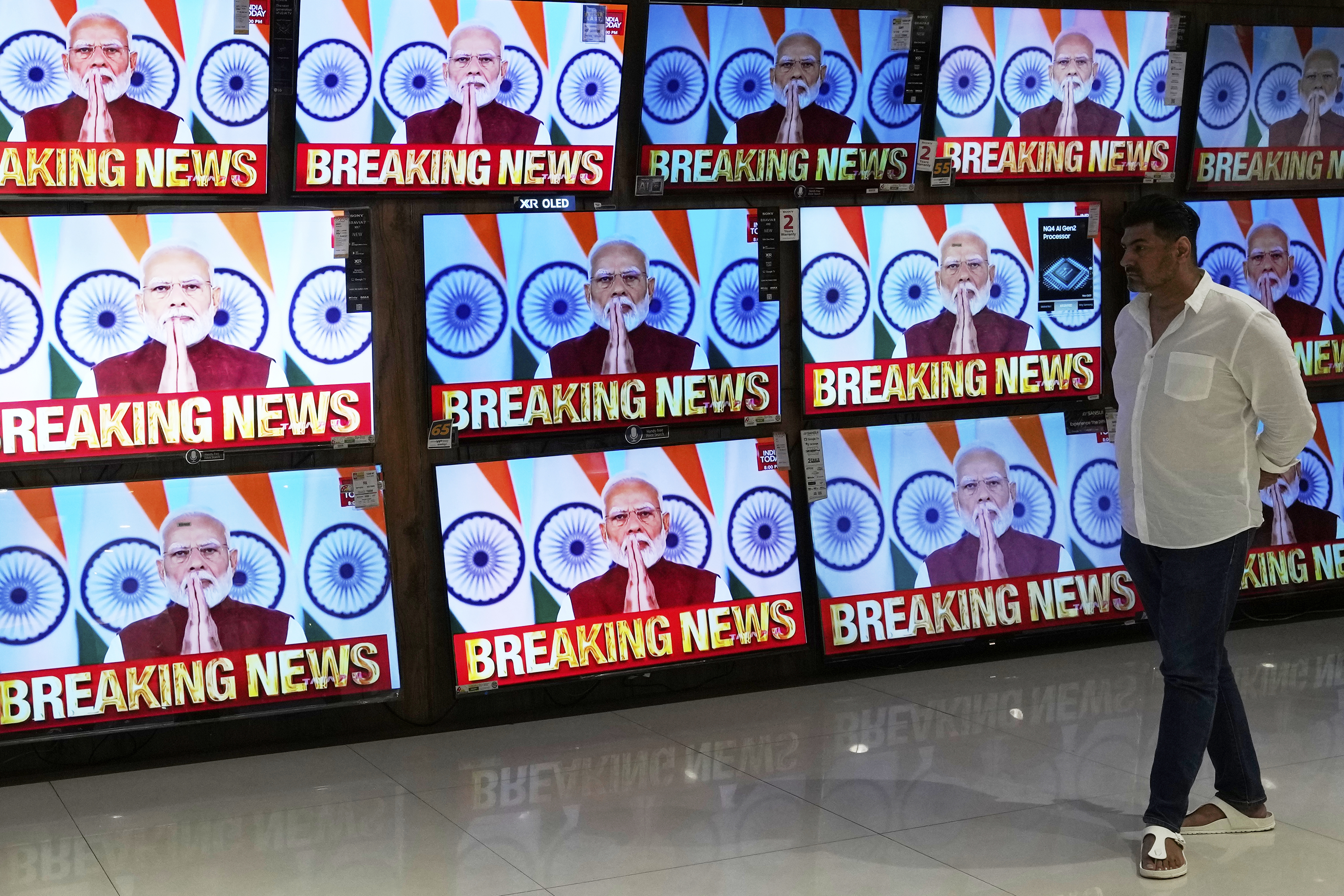 A man watches the live telecast of Indian Prime Minister Narendra Modi's speech on television screens at a shopping mall after 'Operation Sindoor' in Mumbai, India, Monday, May 12, 2025. (AP Photo/Rajanish Kakade)