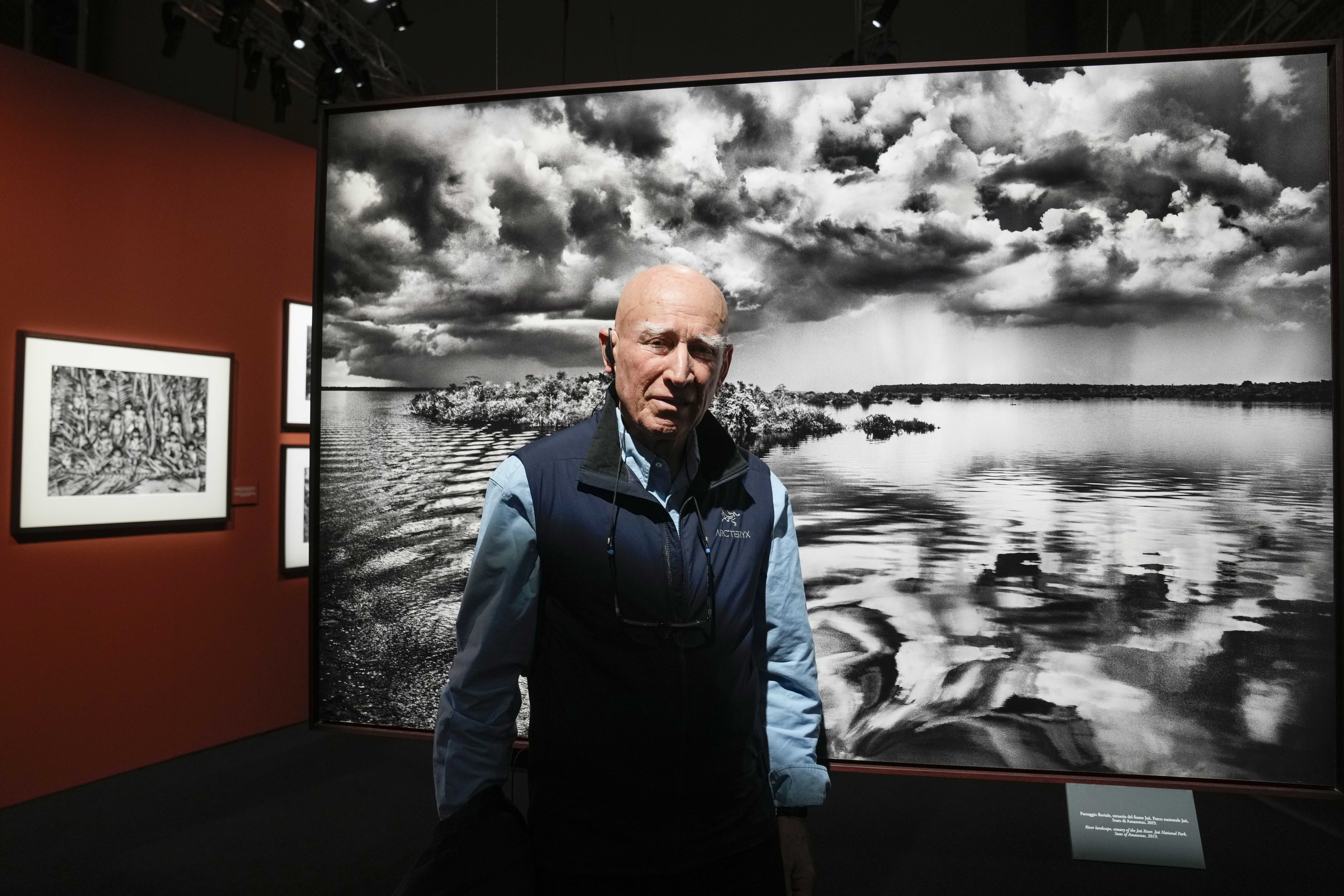 Sebastiao Salgado stands in front of his black-and-white photography