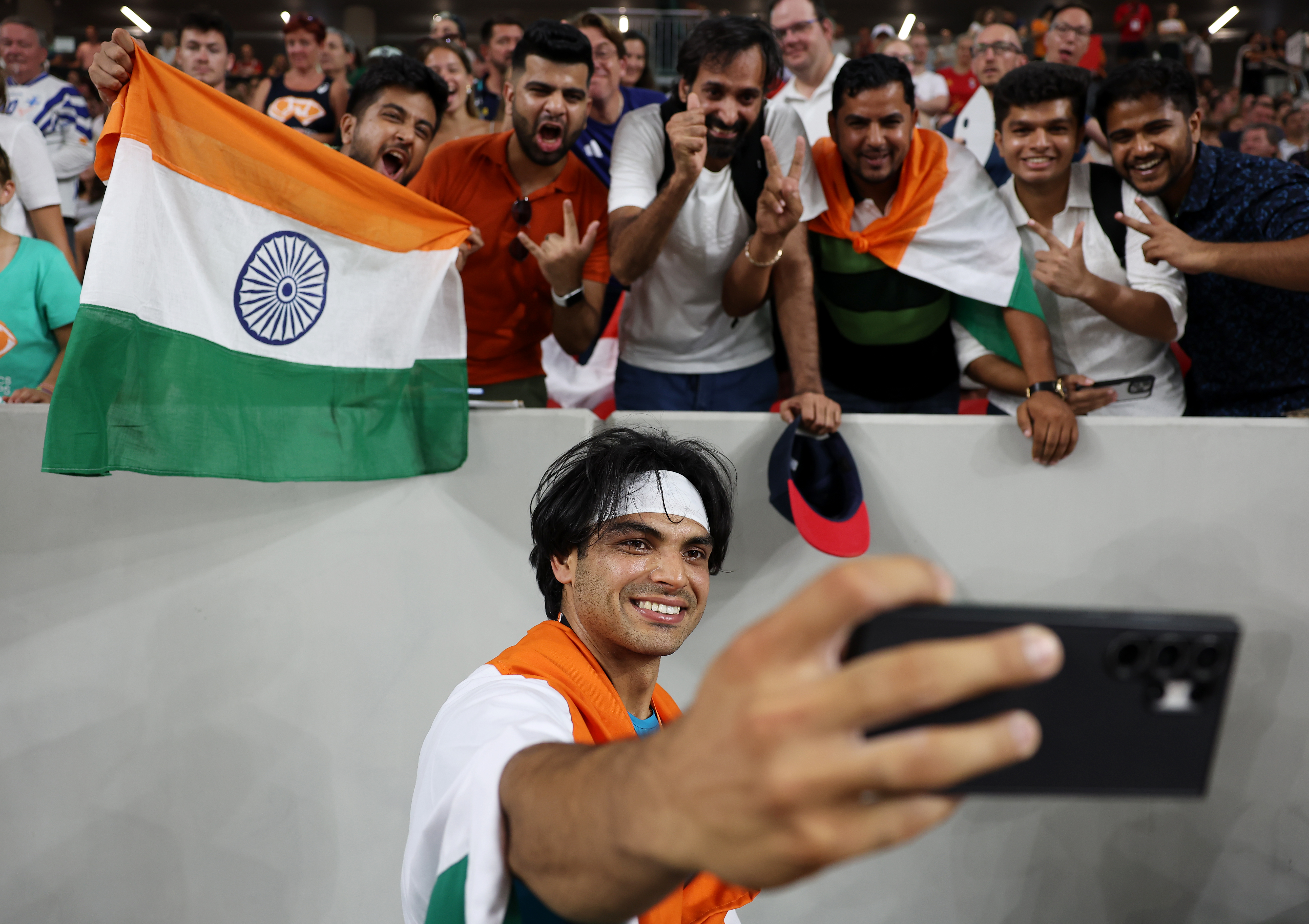 BUDAPEST, HUNGARY - AUGUST 27: Gold medalist Neeraj Chopra of Team India celebrates winning by taking selfies with fans after the Men's Javelin Throw Final during day nine of the World Athletics Championships Budapest 2023 at National Athletics Centre on August 27, 2023 in Budapest, Hungary. (Photo by Steph Chambers/Getty Images)