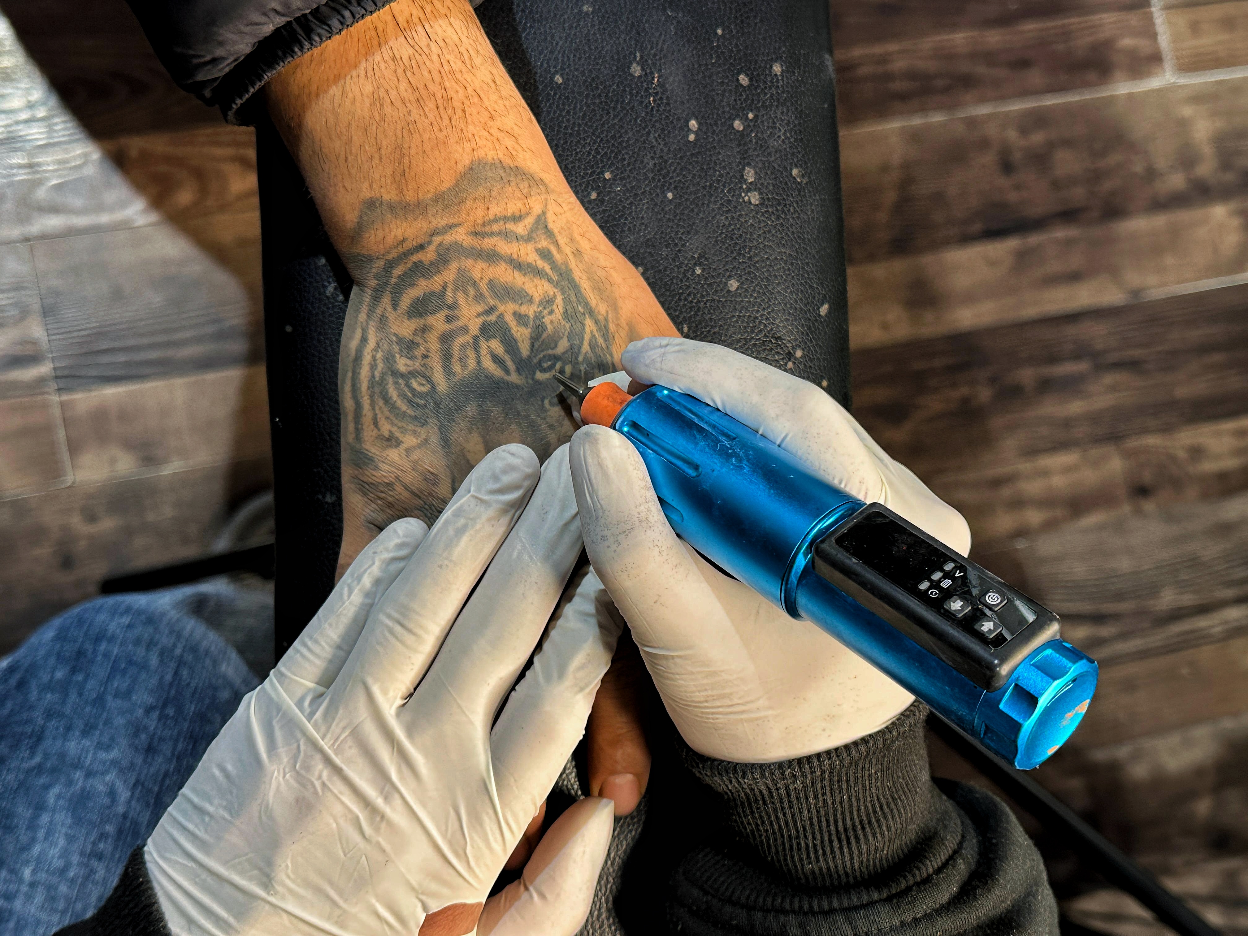 Photo 6: A man gets a tiger tattoo inked on his hand.