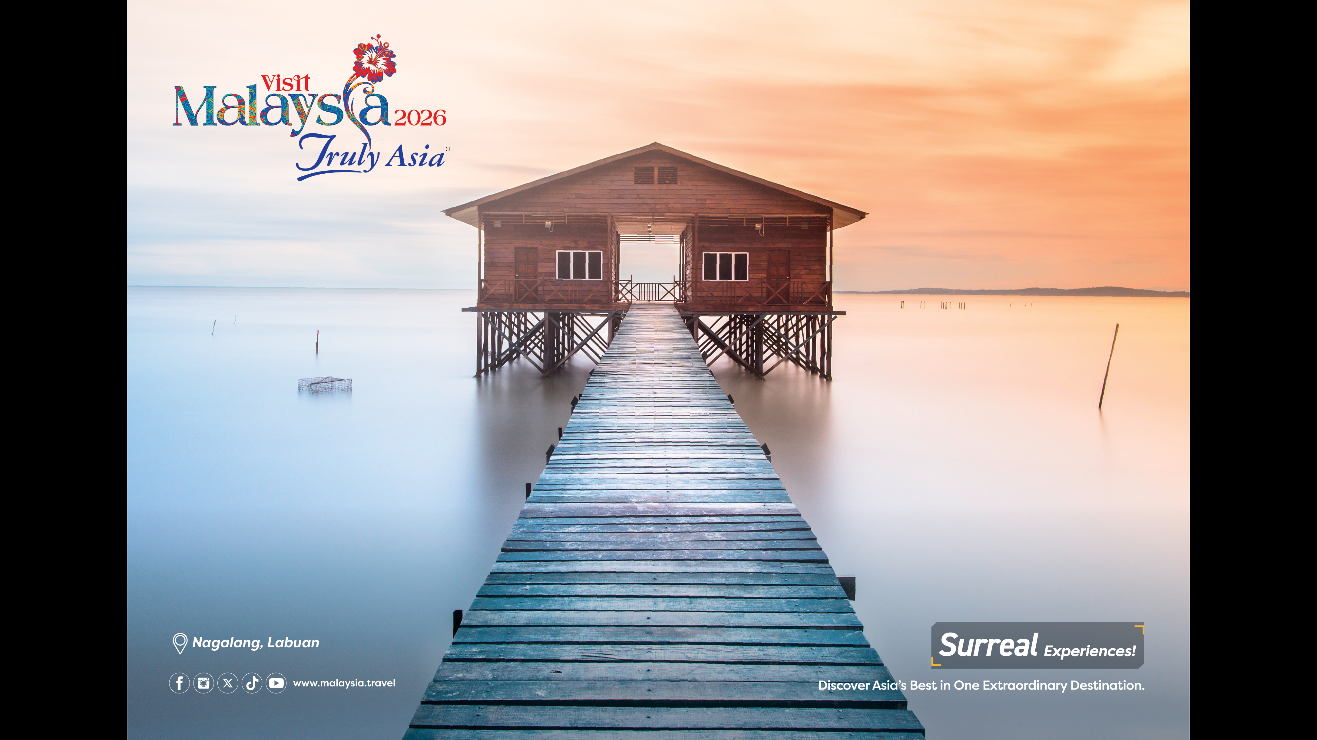 A wooden walkway over the water leads to a wooden building on stilts