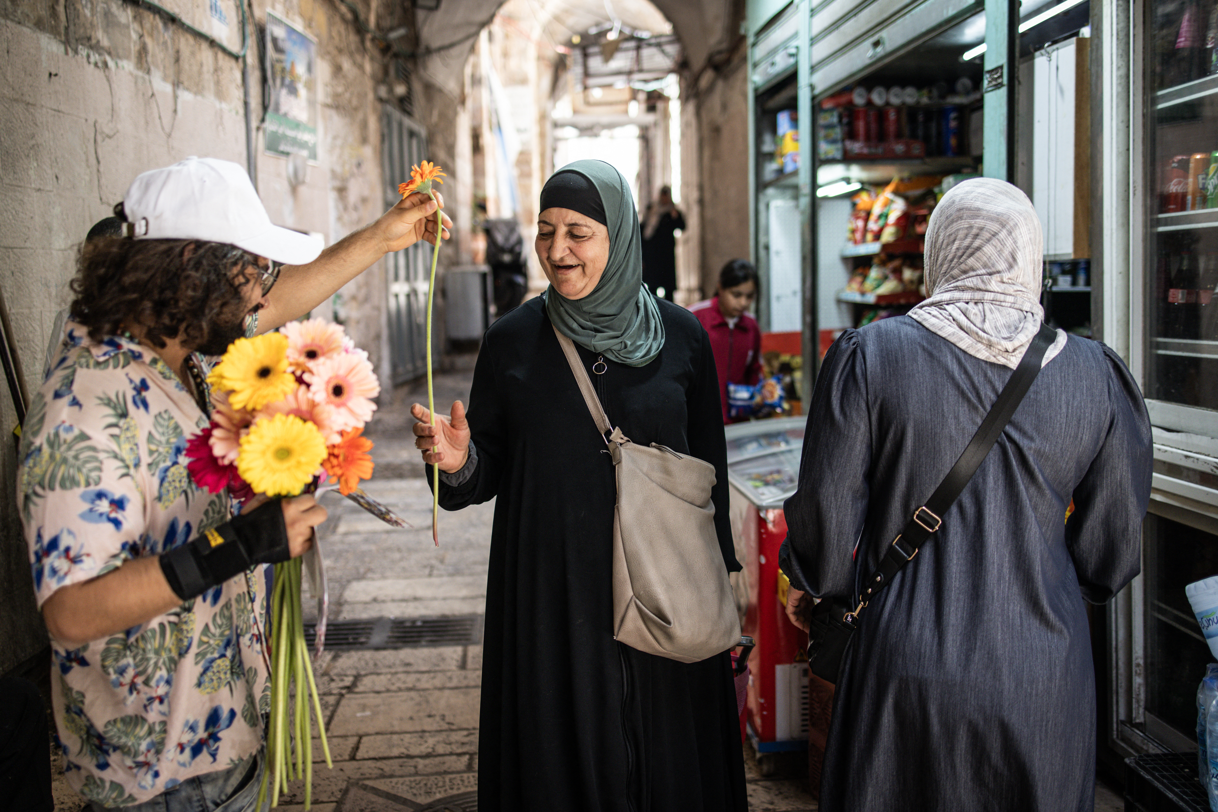 A solidarity activist hands out flowers to Palestinians in Jerusalem's Old City during a flag march by Israeli right-wing activists to mark Jerusalem Day on May 26, 2025, commemorating the Israeli army's 1967 capture of the city's eastern sector during the Arab-Israeli war.