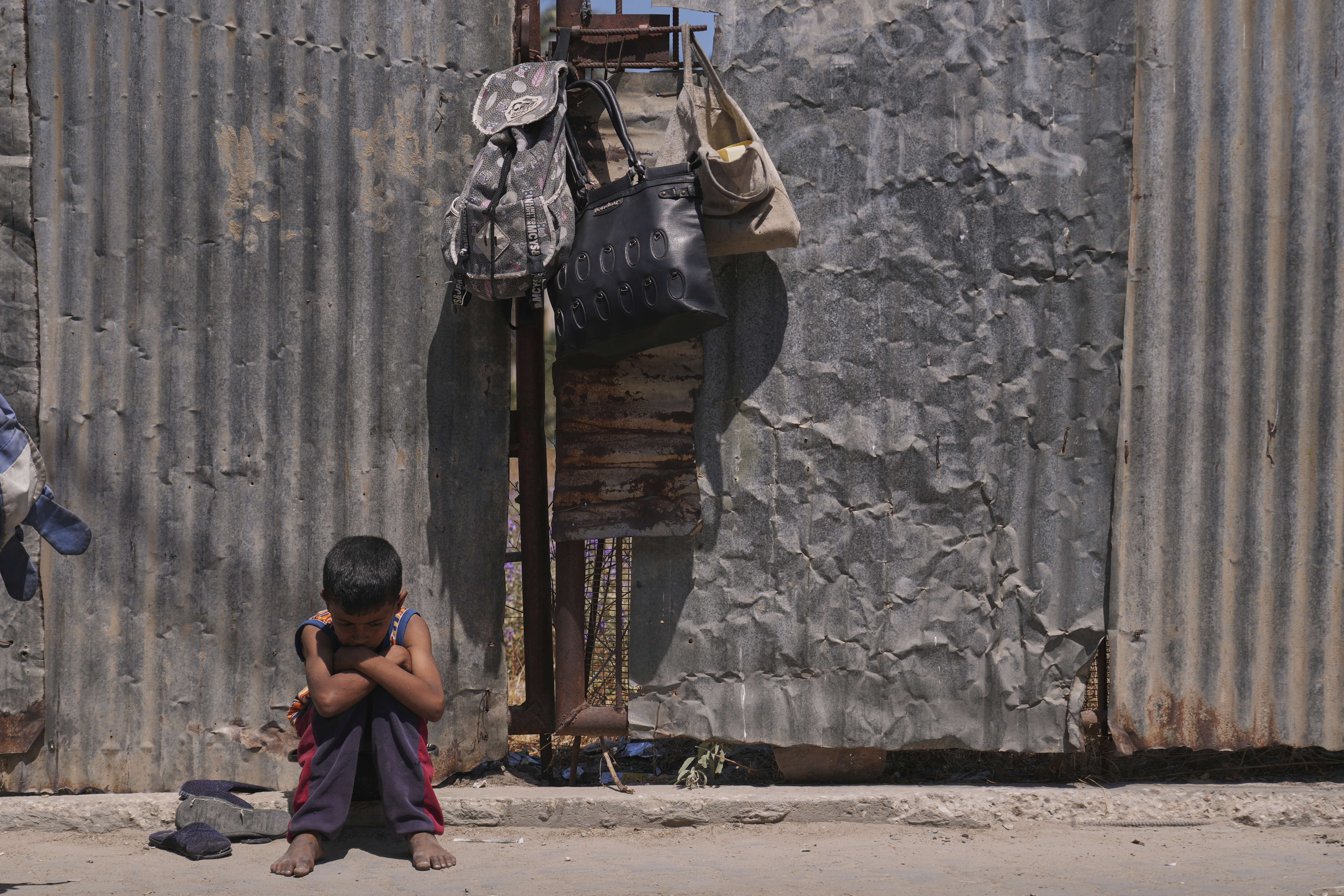 A Palestinian boy sits on the curb as he waits near a food distribution kitchen in Deir al-Balah, Gaza Strip, Friday, May 30, 2025. (AP Photo/Abdel Kareem Hana)