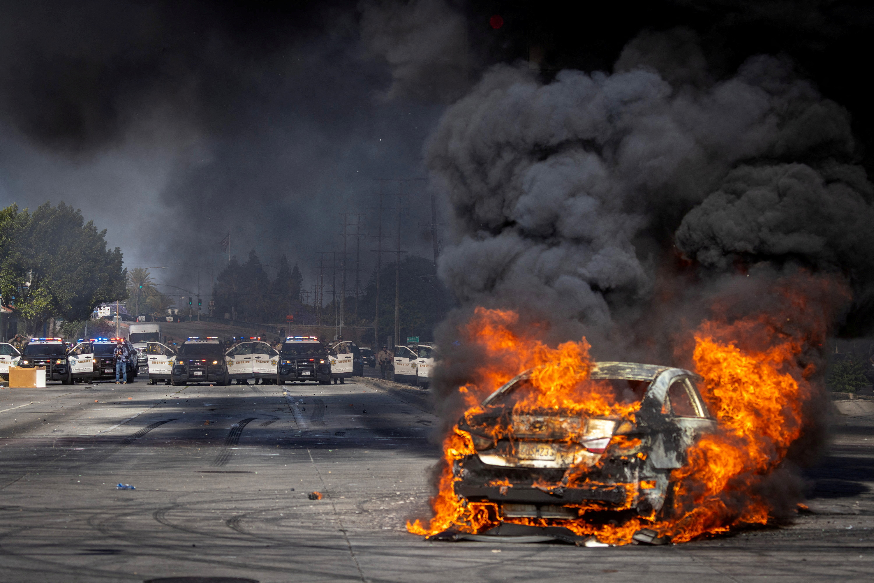 A car burns on Atlantic Boulevard during a standoff by protesters and law enforcement, following multiple detentions by Immigration and Customs Enforcement (ICE), in the Los Angeles County city of Paramount, California, U.S., June 7, 2025.