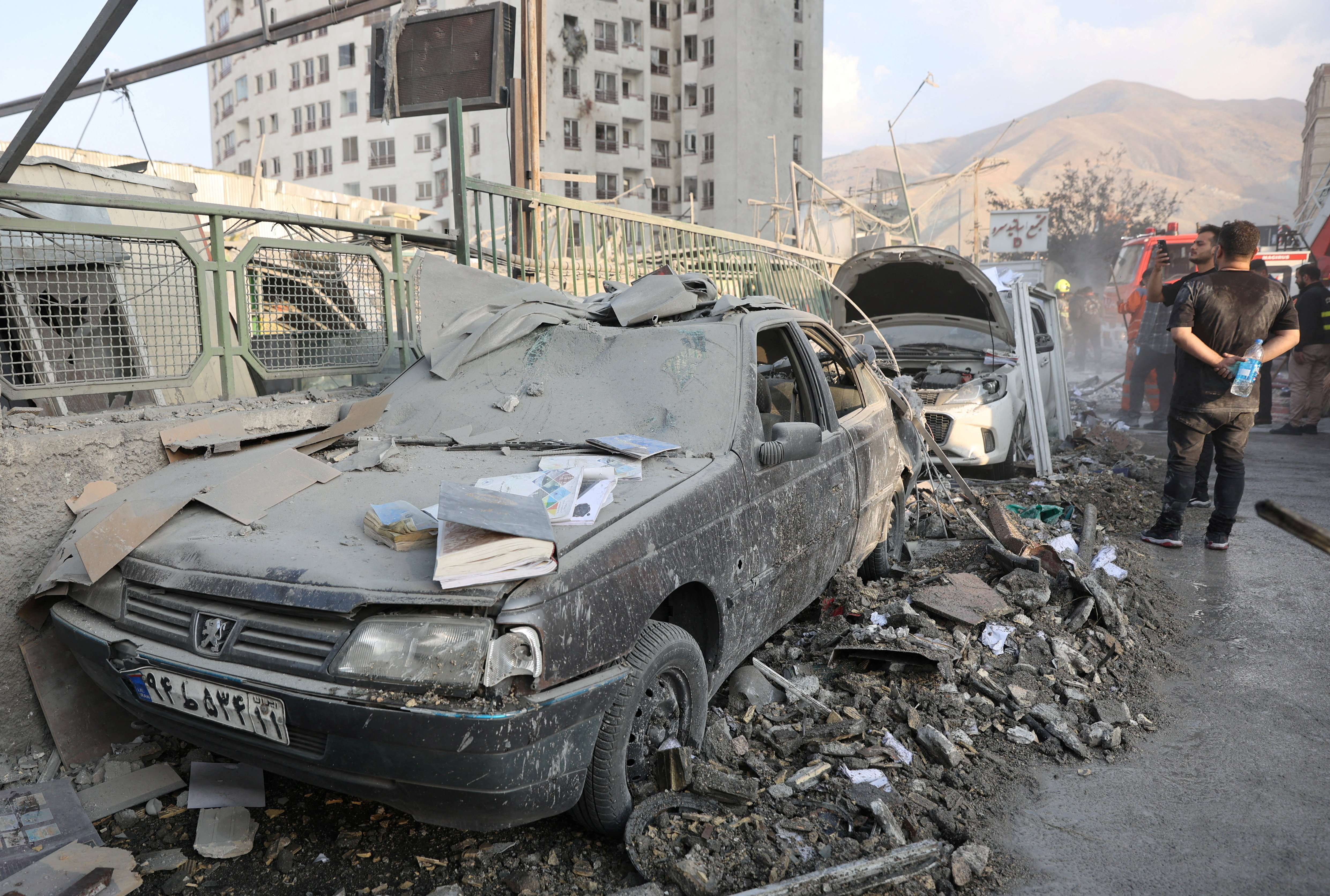 People gather near damaged vehicles in the aftermath of Israeli strikes, in Tehran, Iran, June 13, 2025. Majid Asgaripour/WANA (West Asia News Agency) via REUTERS ATTENTION EDITORS - THIS PICTURE WAS PROVIDED BY A THIRD PARTY TPX IMAGES OF THE DAY
