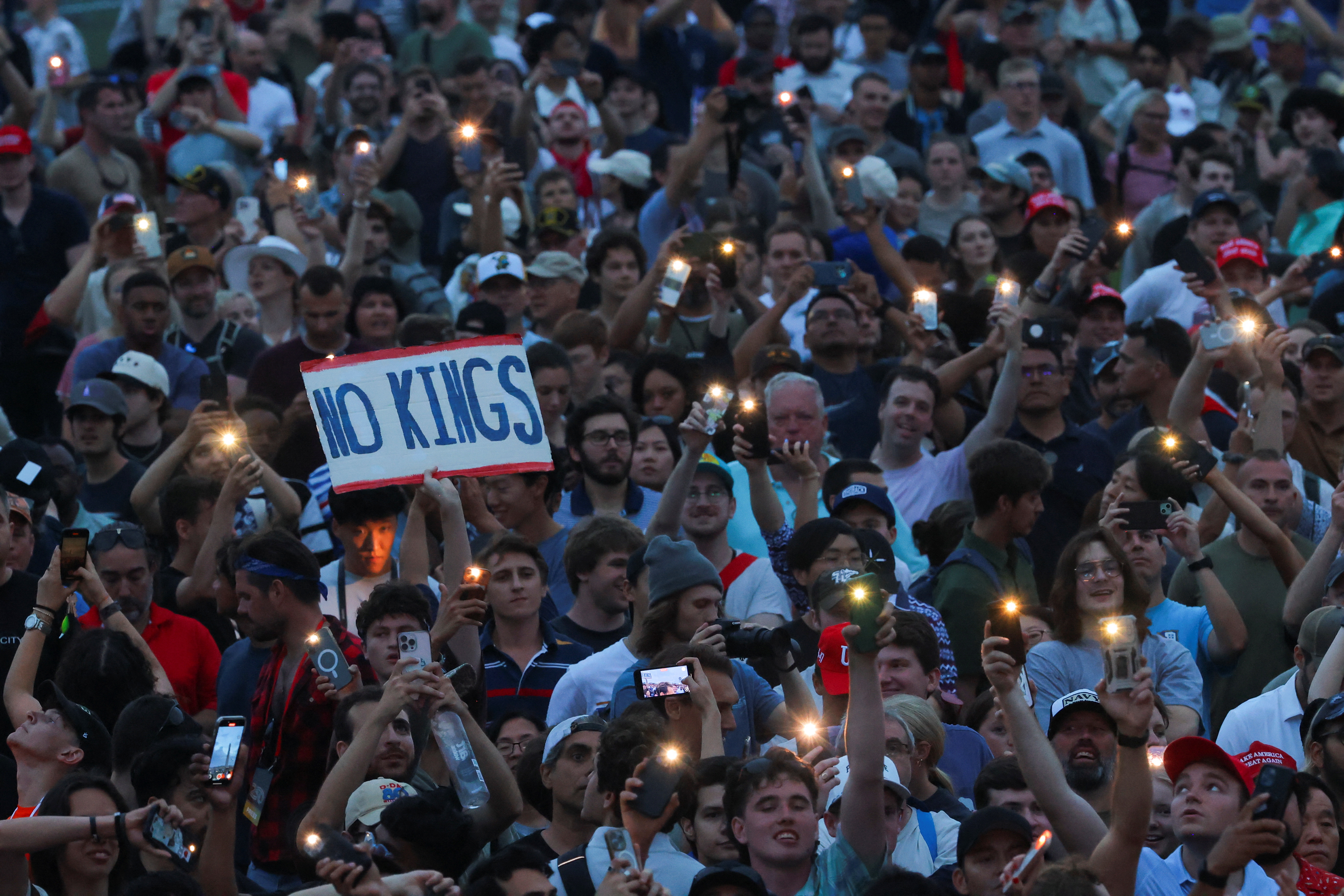 A person holds up a "No Kings" sign in protest against U.S. President Donald Trump's policies and federal immigration sweeps, during the U.S. Army’s 250th Birthday Festival in Washington, D.C., US, June 14, 2025. REUTERS/Carlos Barria