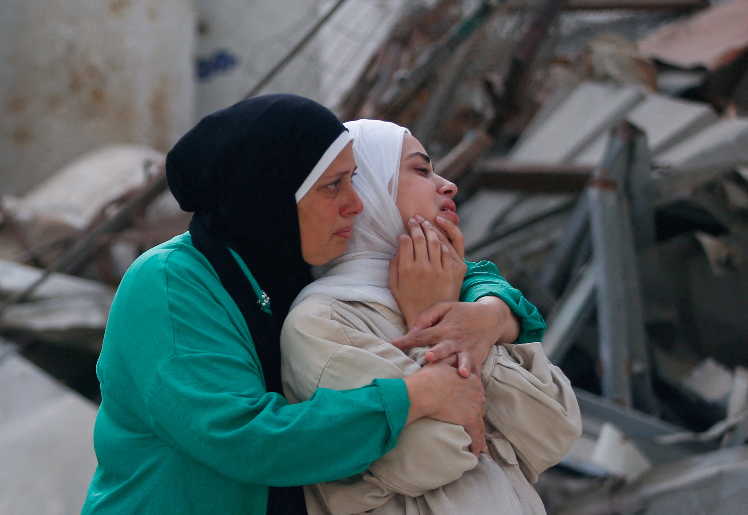 Women embrace, while mourning loved ones during the funeral of Palestinians killed by Israeli fire yesterday, while seeking aid in northern Gaza