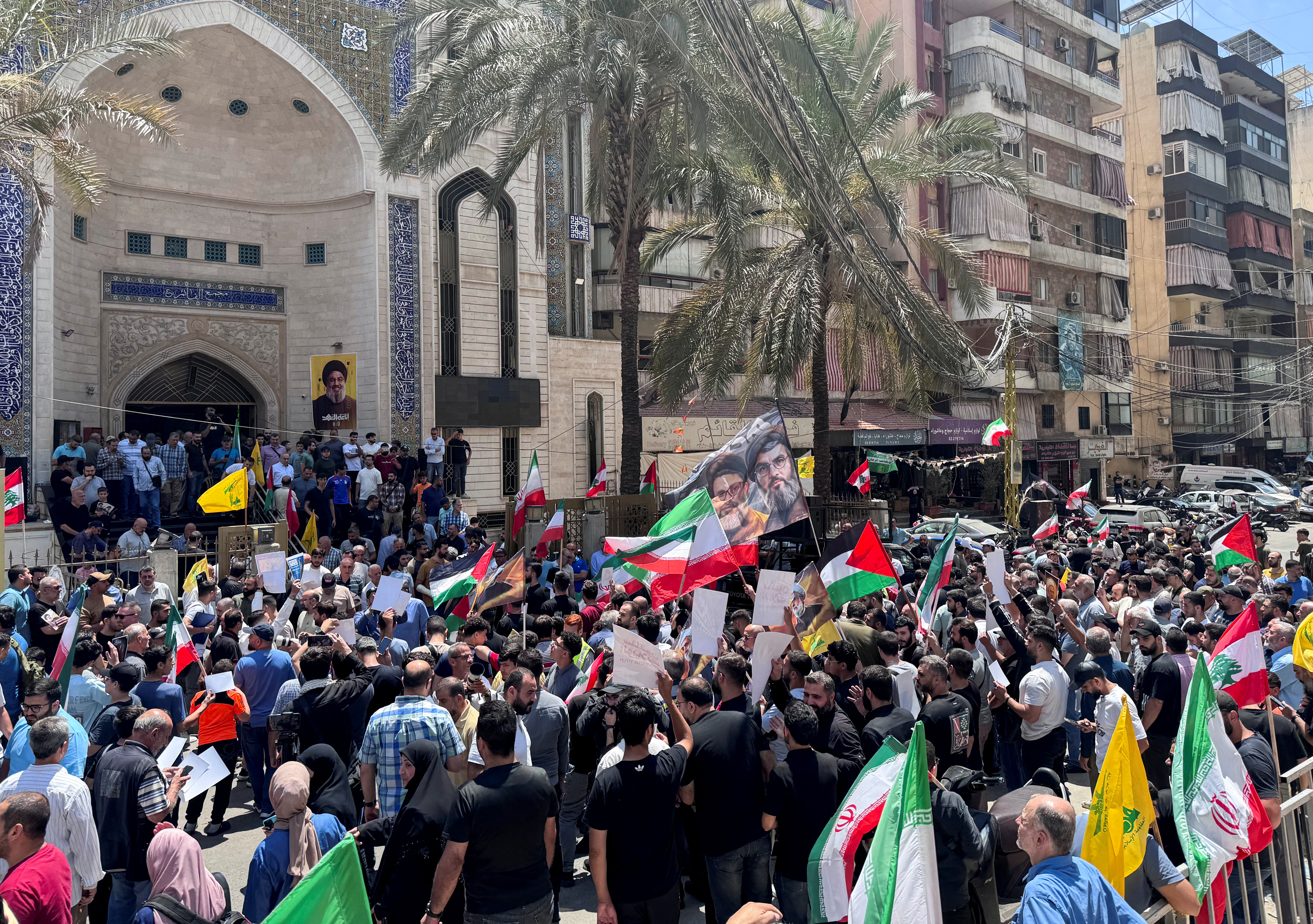 Demonstrators hold flags as they gather for a rally in solidarity with Iran after Friday prayers, at Beirut southern suburbs.